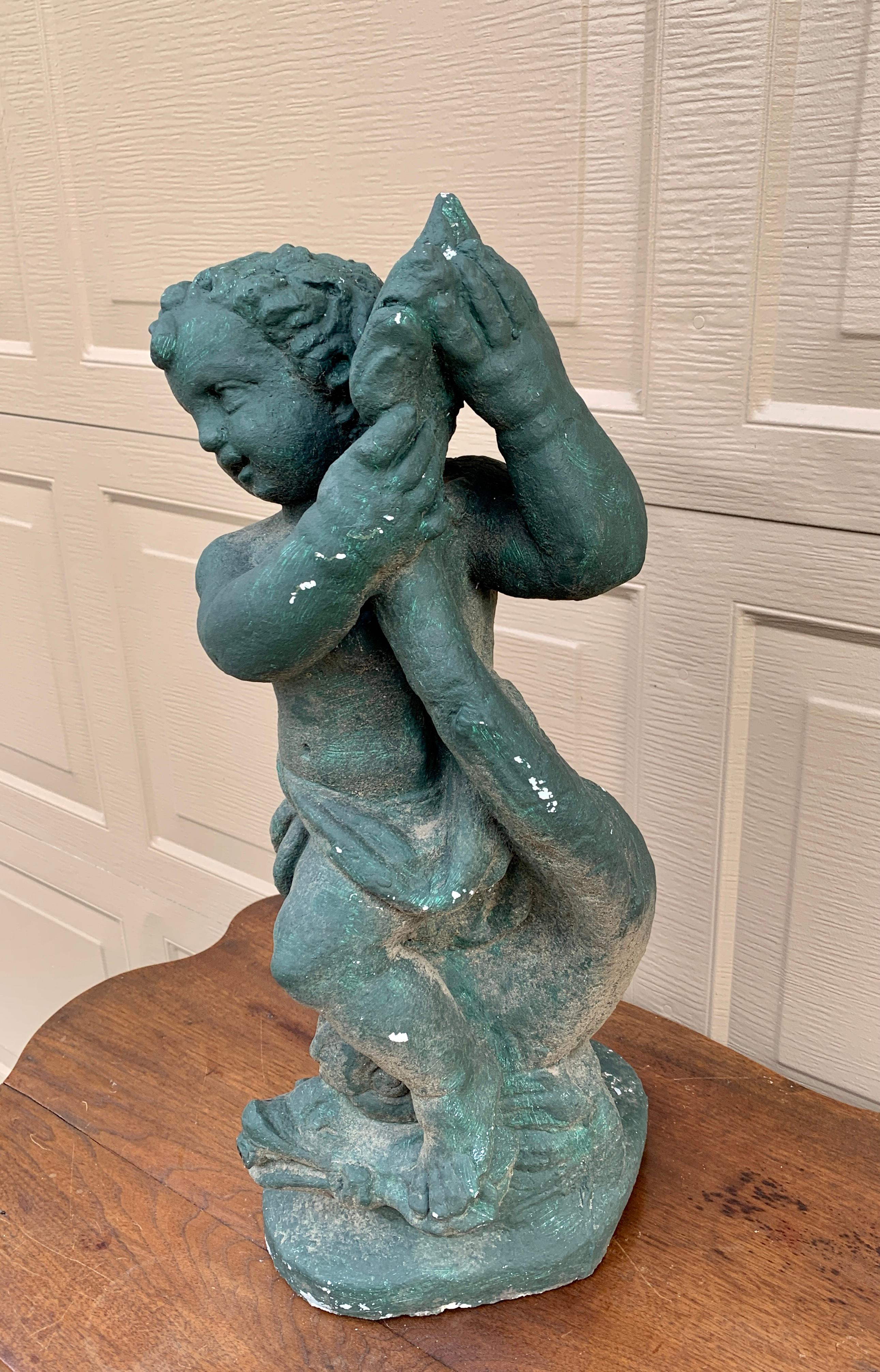 A stunning cast stone green statue of a cherub or putti holding a fish. The fish's mouth was once a fountain and could still be used that way if desired. The piece is the perfect accent in a garden. 

USA, Late 20th Century

Measures: 9