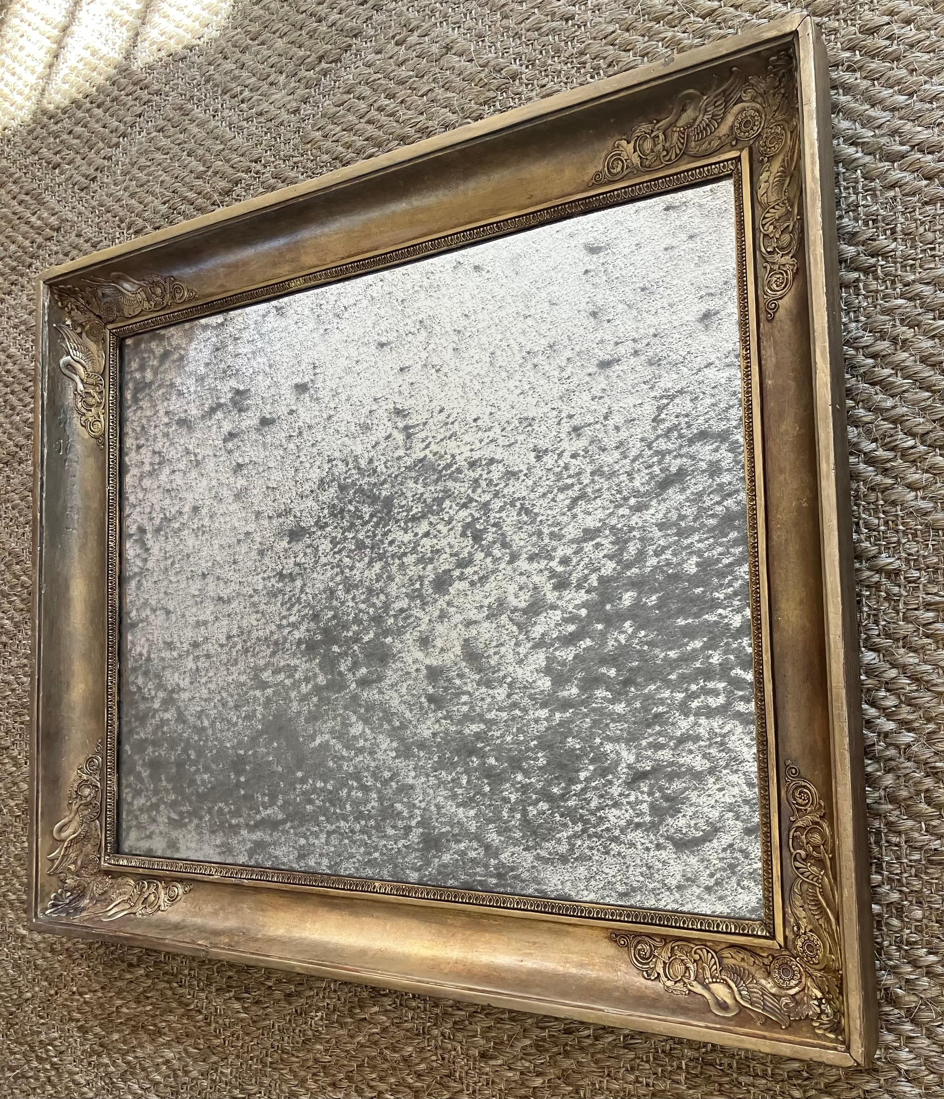 Specchio neoclassico italiano intagliato in oro. Cornice in legno intagliato e gesso di Charles X in oro con decorazione neoclassica ad anthemion e cigno ad angolo che incornicia una successiva lastra di specchio in vetro al mercurio. Italia, 1830