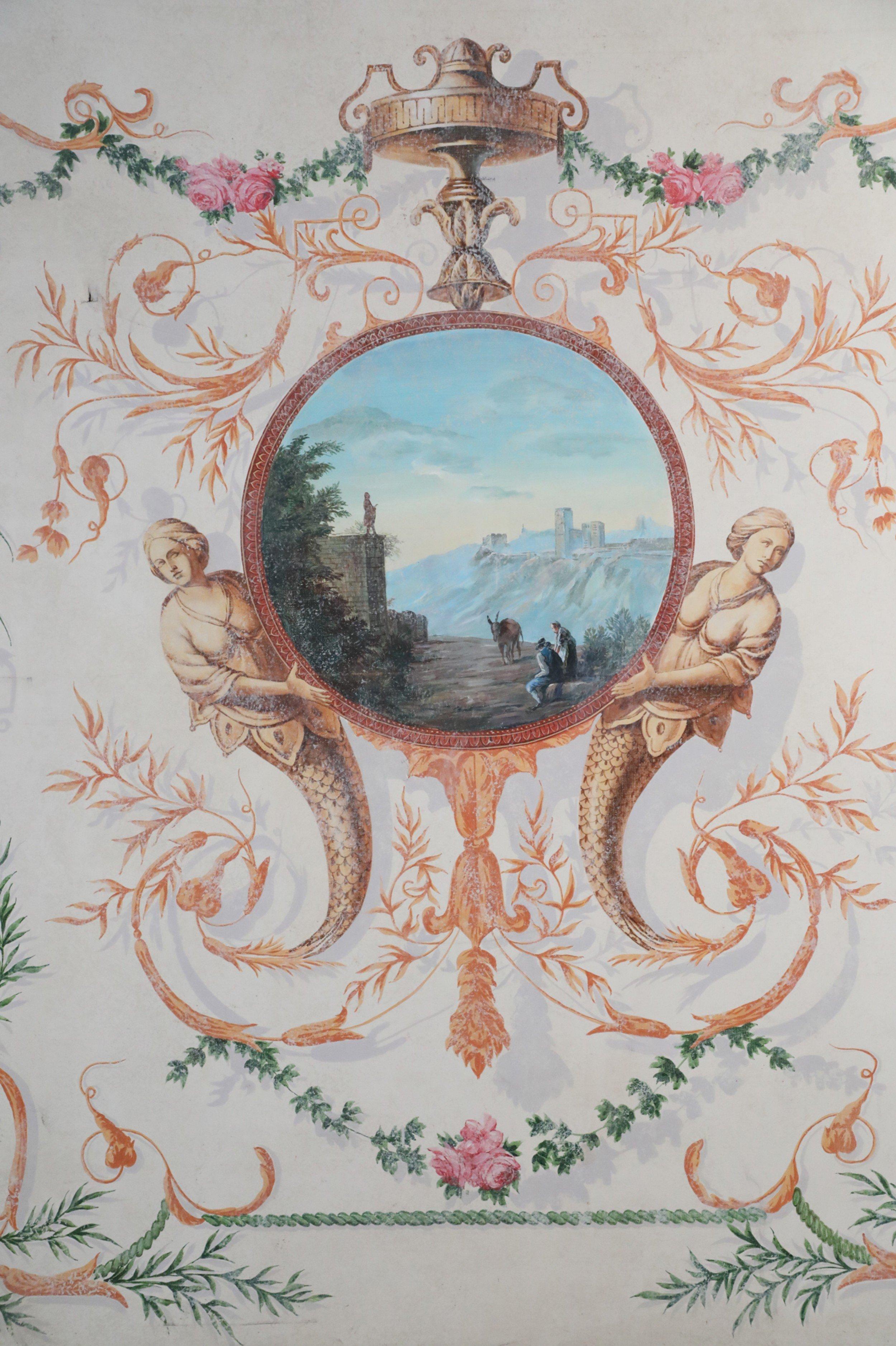 Vintage Neoclassical-Style (20th Century) acrylic painting featuring a central circular landscape scene of men and a donkey at a mountain fortress overlook, held by two mermaids and an elaborate shadowed foliate border of leaves, flowers and urns,