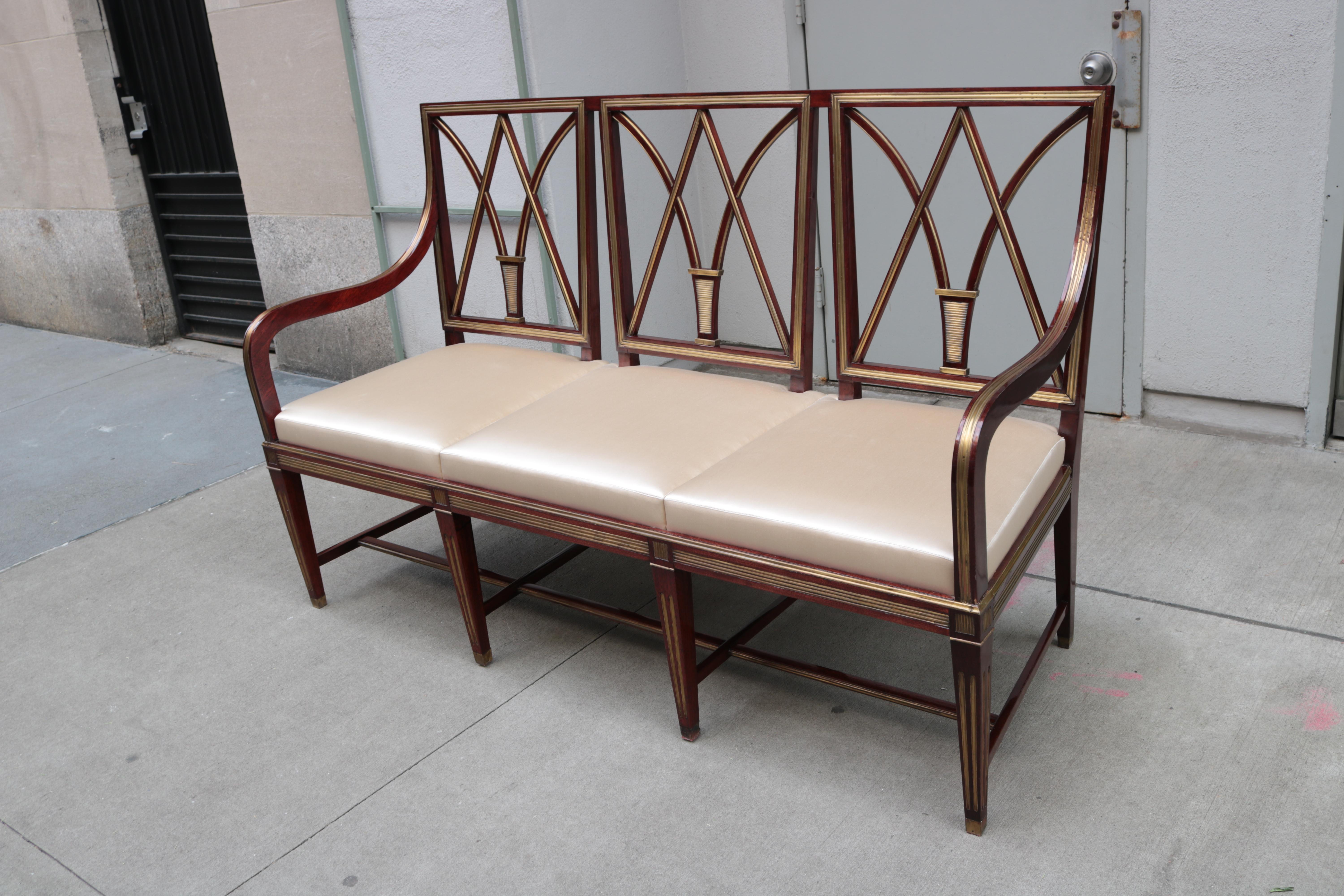 A fine neoclassical three seat bench. 
Mahogany with patinated brass inlay, details and sabots.
