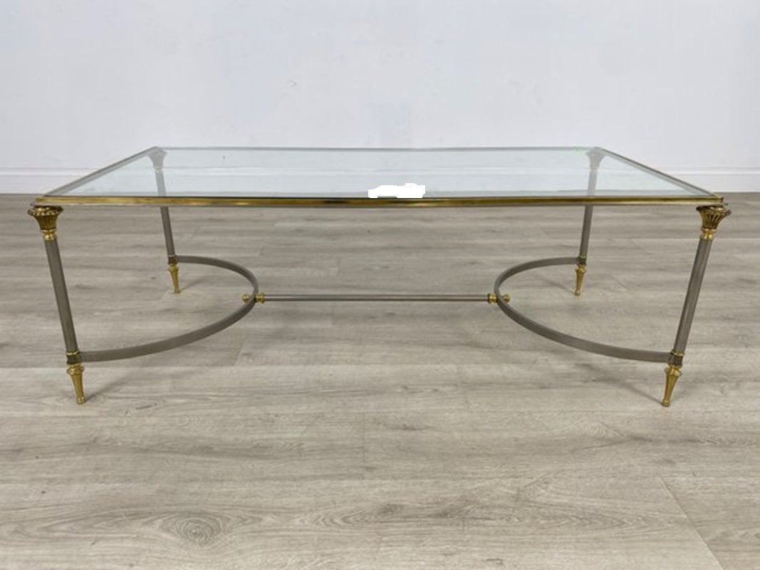 Table basse néoclassique en acier brossé et laiton avec plateau en verre inséré, de style Maison Jansen. Circa 1960s- 1970s.  Estampillé Italie sur le dessous des pieds. Veuillez noter l'usure due à l'âge, y compris l'oxydation mineure sur la