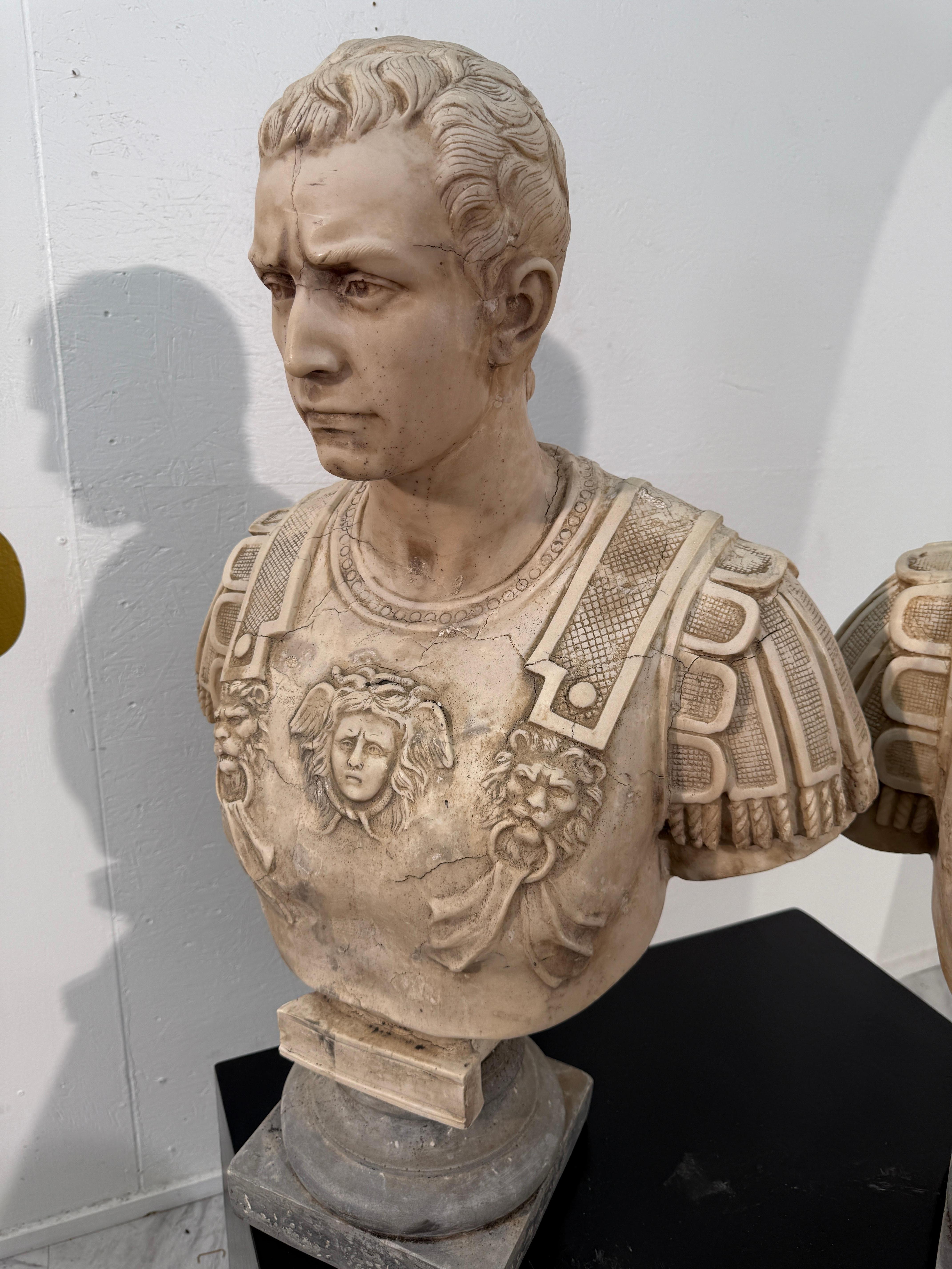 Un busto in marmo neoclassico finemente dettagliato che raffigura un generale romano in armatura completa, ornato da intricati rilievi di figure mitologiche e da un motivo di testa di leone al centro della corazza. Il viso scolpito trasmette