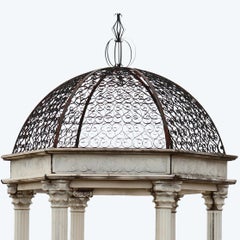 Gazebo neoclásico con columnas de mármol y cúpula calada de hierro forjado con volutas