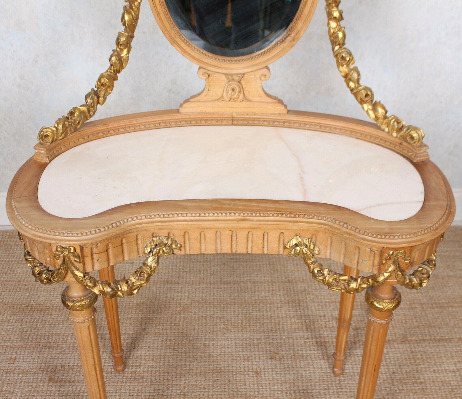 A fine quality marble and satinwood mirrored dressing table.

The oval beveled mirror on supports adorned with finely carved gilt rope twist swags matching the apron of the marble inset table and raised on slender fluted tapering legs.

An aged