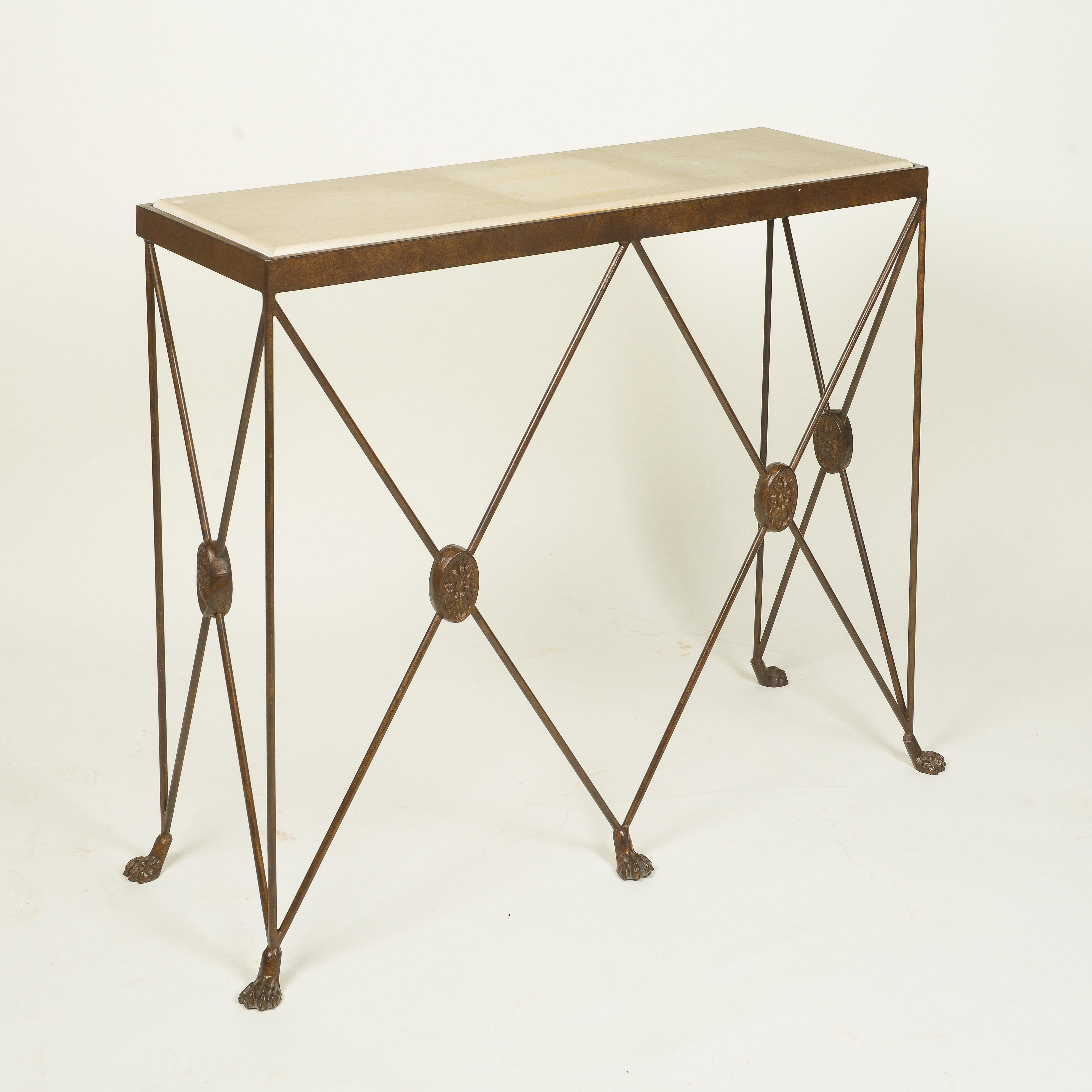 The rectangular white marble top set within a metal edge; raised on X-form supports joined by oval floral rosettes, terminating in paw feet; with an antiqued gilt finish to the metal.