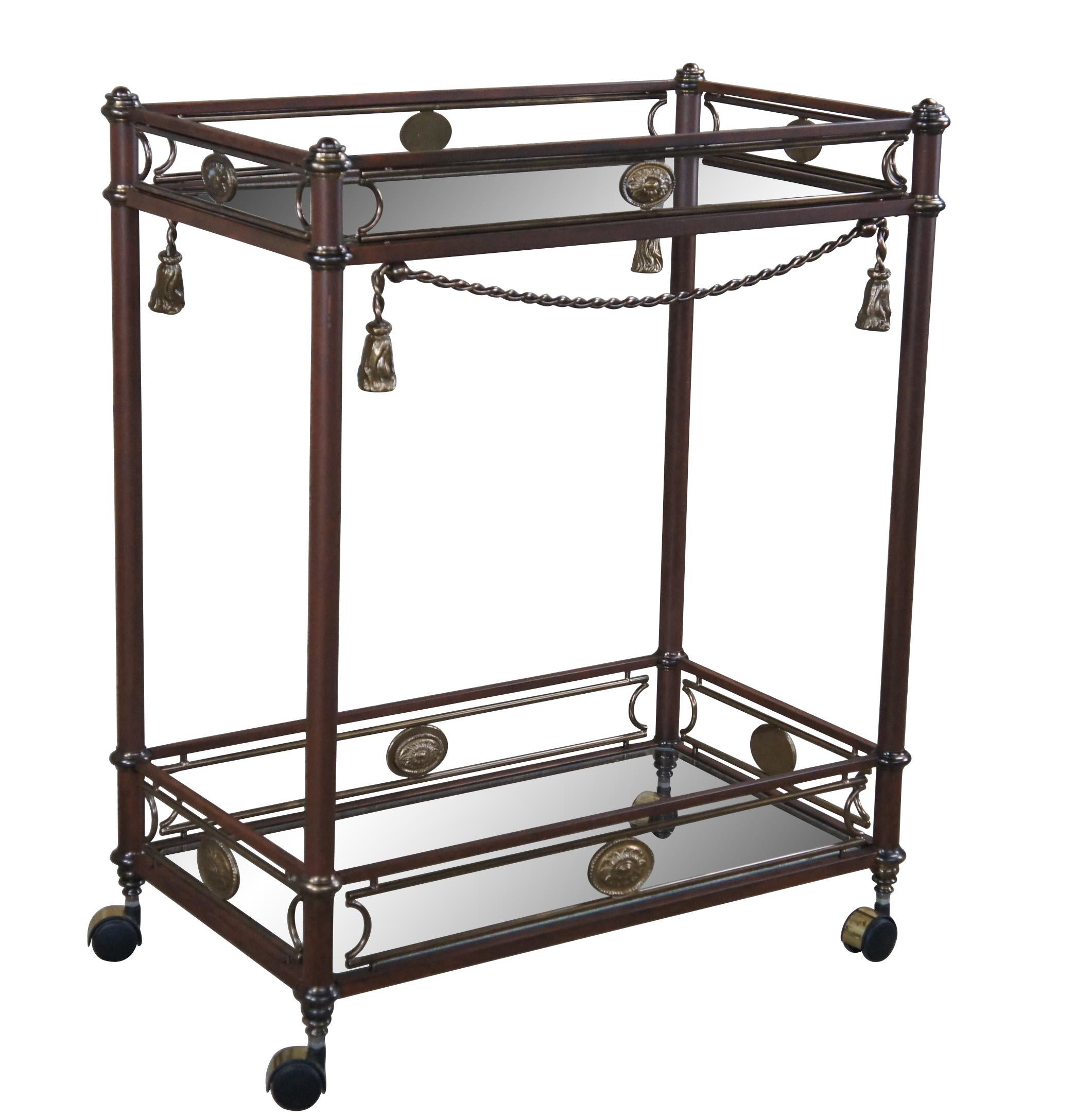 Vintage Butlers tea trolly or swivel bar cart.  Made of metal and glass featuring tiered form with brass accented upper and lower galleries and Neoclassical medallions and tassels.  

Dimensions:
15.5