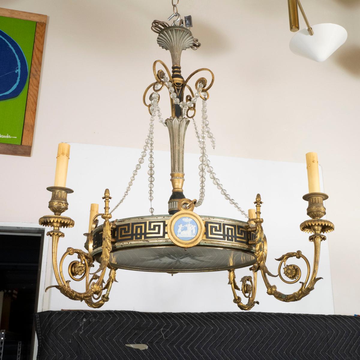 Lustre de style néoclassique avec bras en métal doré, perles de cristal, abat-jour en verre dépoli et gravé et détails en médaillon.