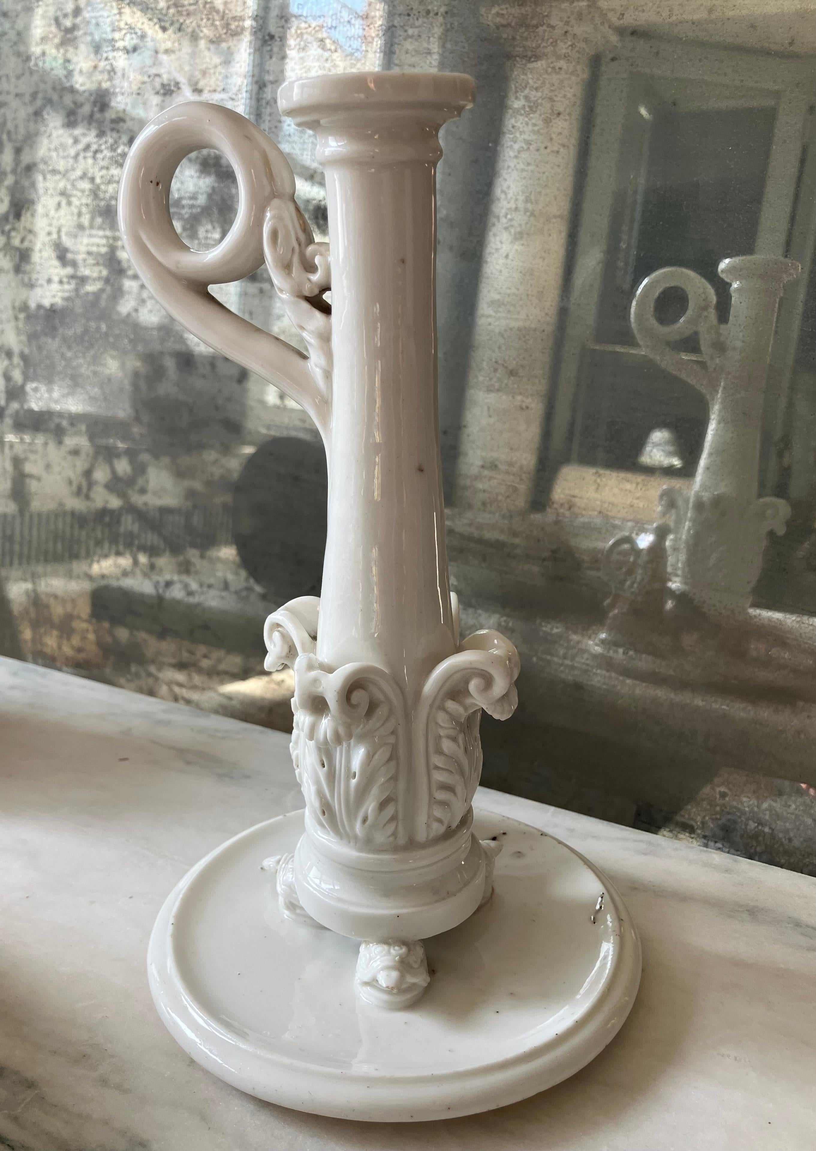 Neoclassical Naples white porcelain candlestick.
Early Ferdinando IV Empire period candlestick of acanthus leaf basket form issuing tapered columnar shaft with scrolled foliate ring handle, all on raised based supported by three turtles on further