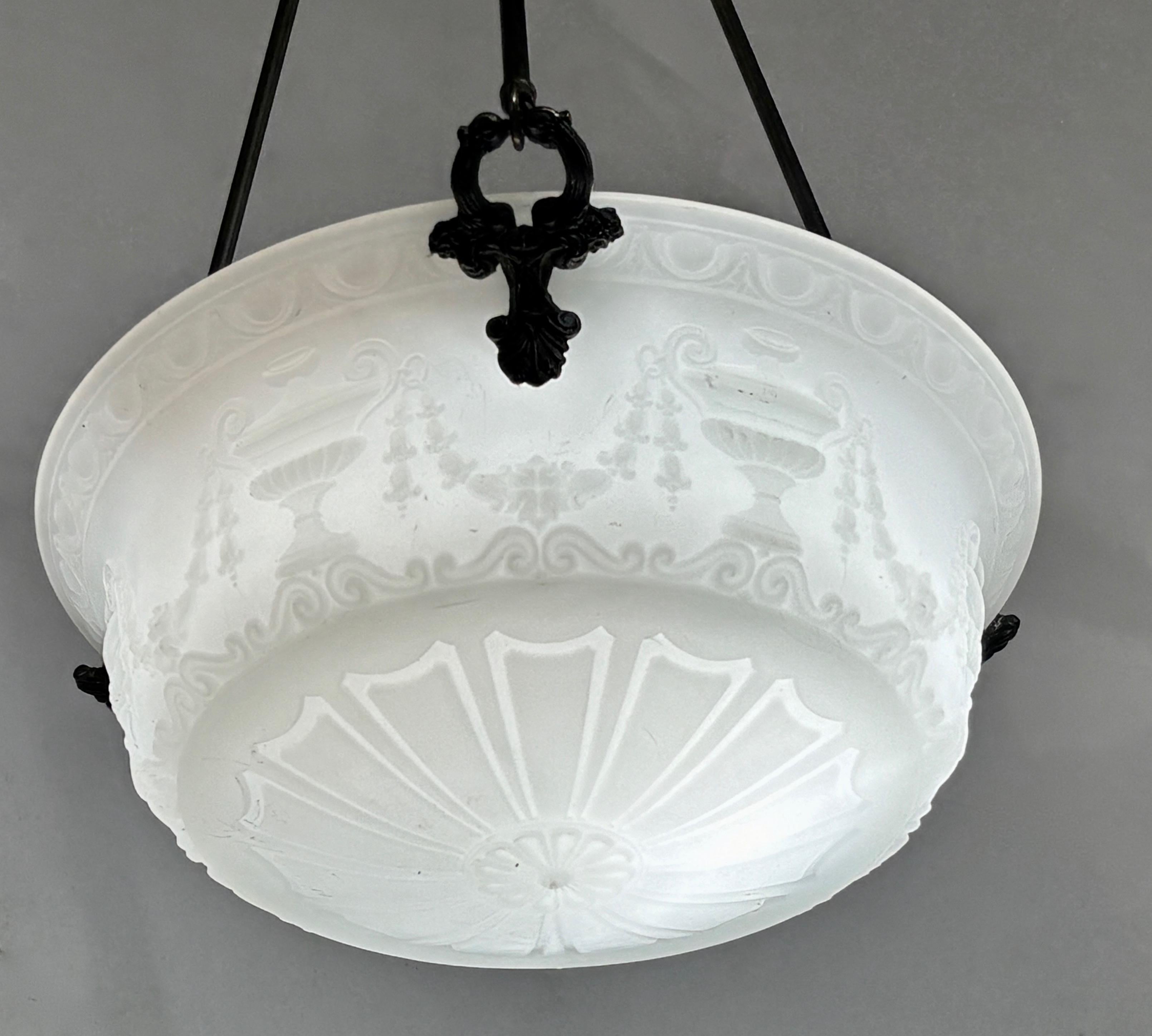 Un meraviglioso pendente da soffitto in vetro bianco opaco fuso di gusto classico, realizzato dalla Chicago Glass Company,  decorato con urne a doppio manico e fasce di foglie d'acanto.  Supporto decorativo in metallo a treppiede, in ottime