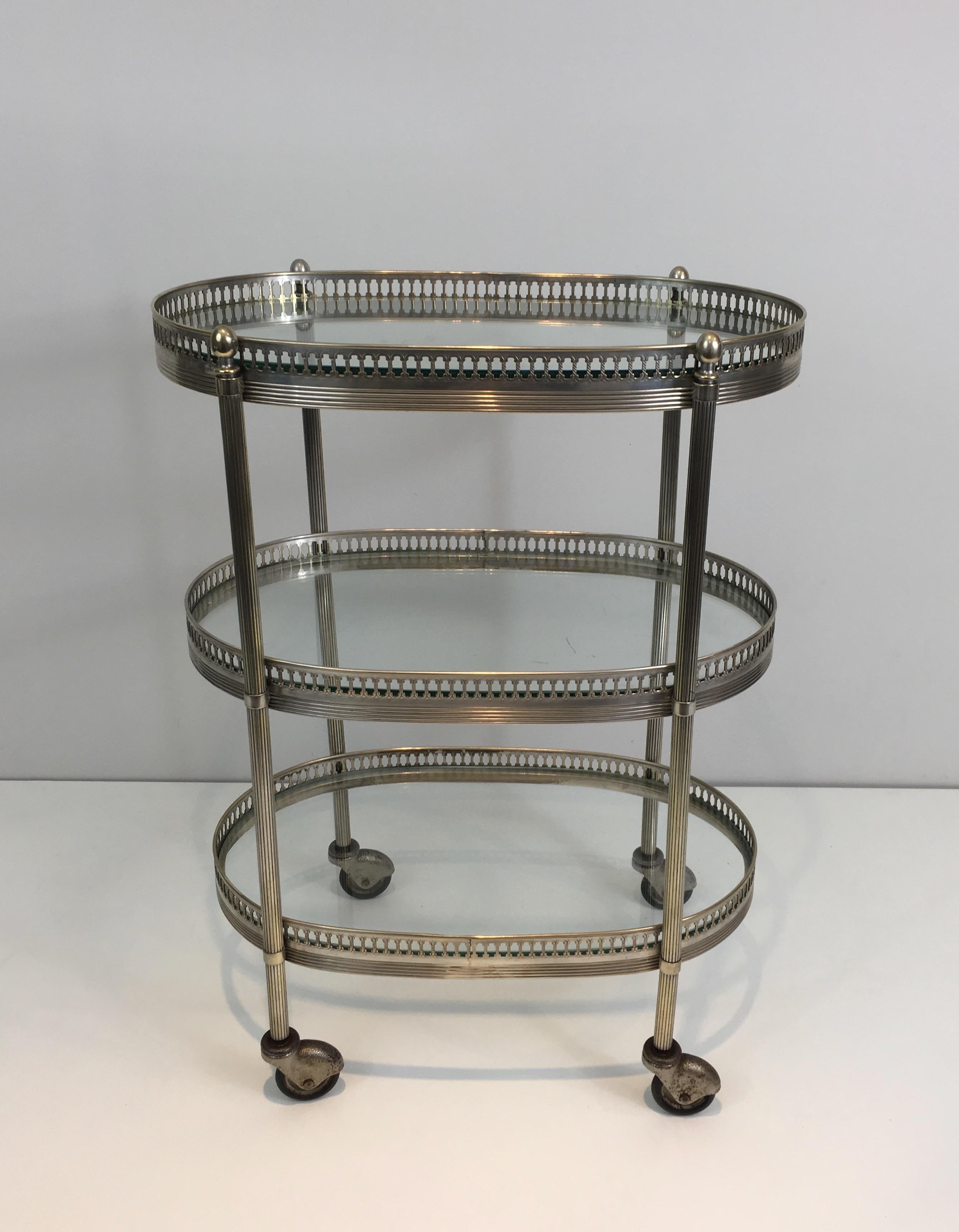 This neoclassical oval bar cart is made of silver plated on brass. This drinks trolley has 3 oval glass shelves. This is French work in the style of Maison Jansen, circa 1940.