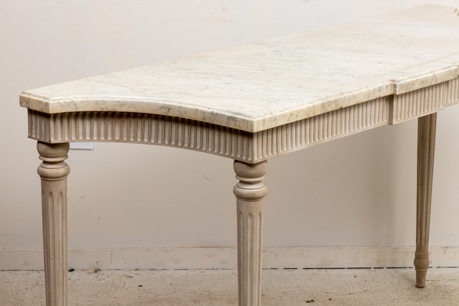 Circa 20th century grisaille painted Neoclassical style console table with fluted apron under turned, tapered, and fluted legs . The piece also features a grey and white 1.50 Inch thick marble top. Made in England. Please note of wear consistent