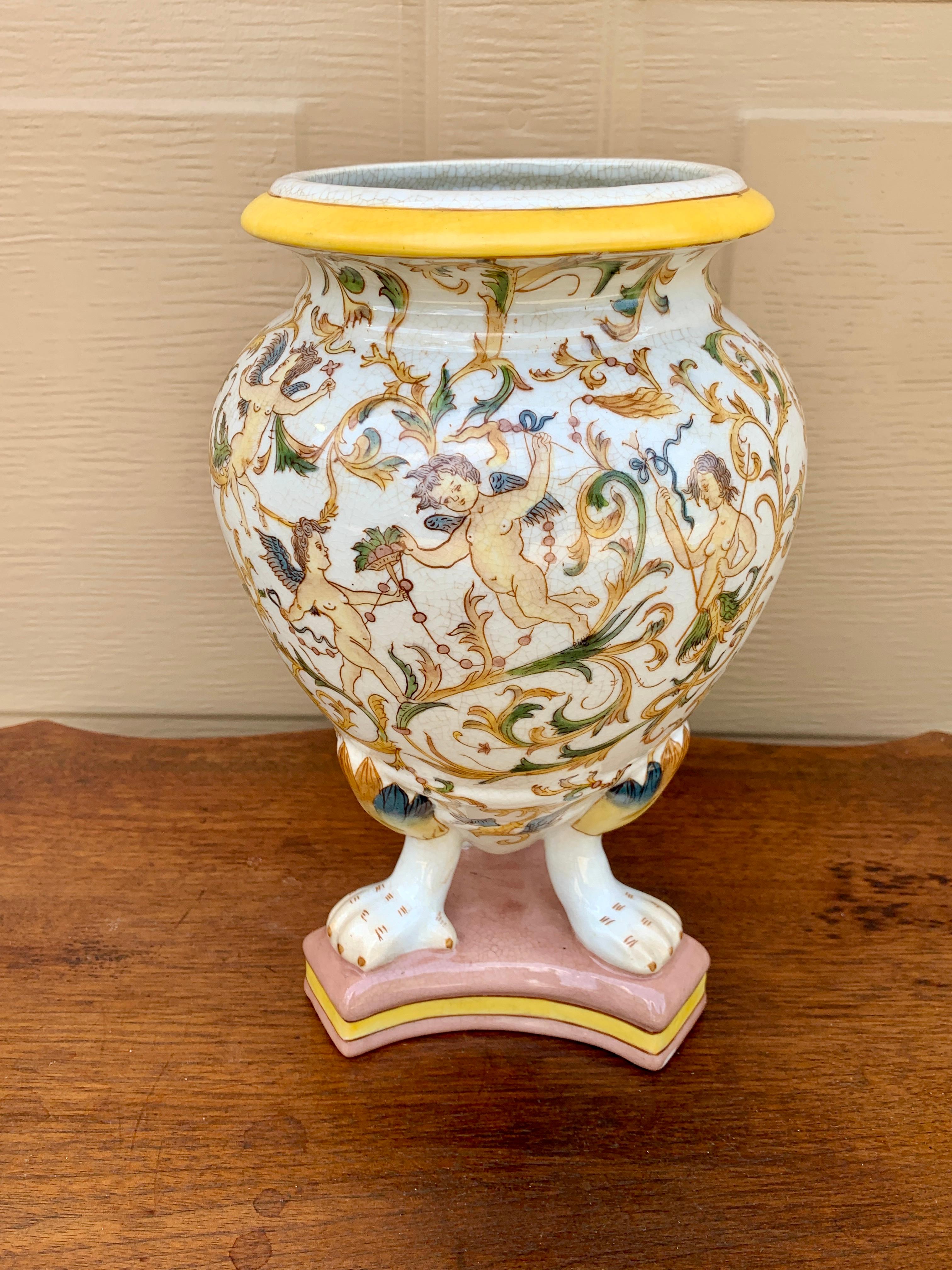 A beautiful painted white, yellow ,pink, blue, and green faience pottery vase on paw feet featuring classical putti and allegorical or mythological symbols

Late 20th Century

Measures: 6.5