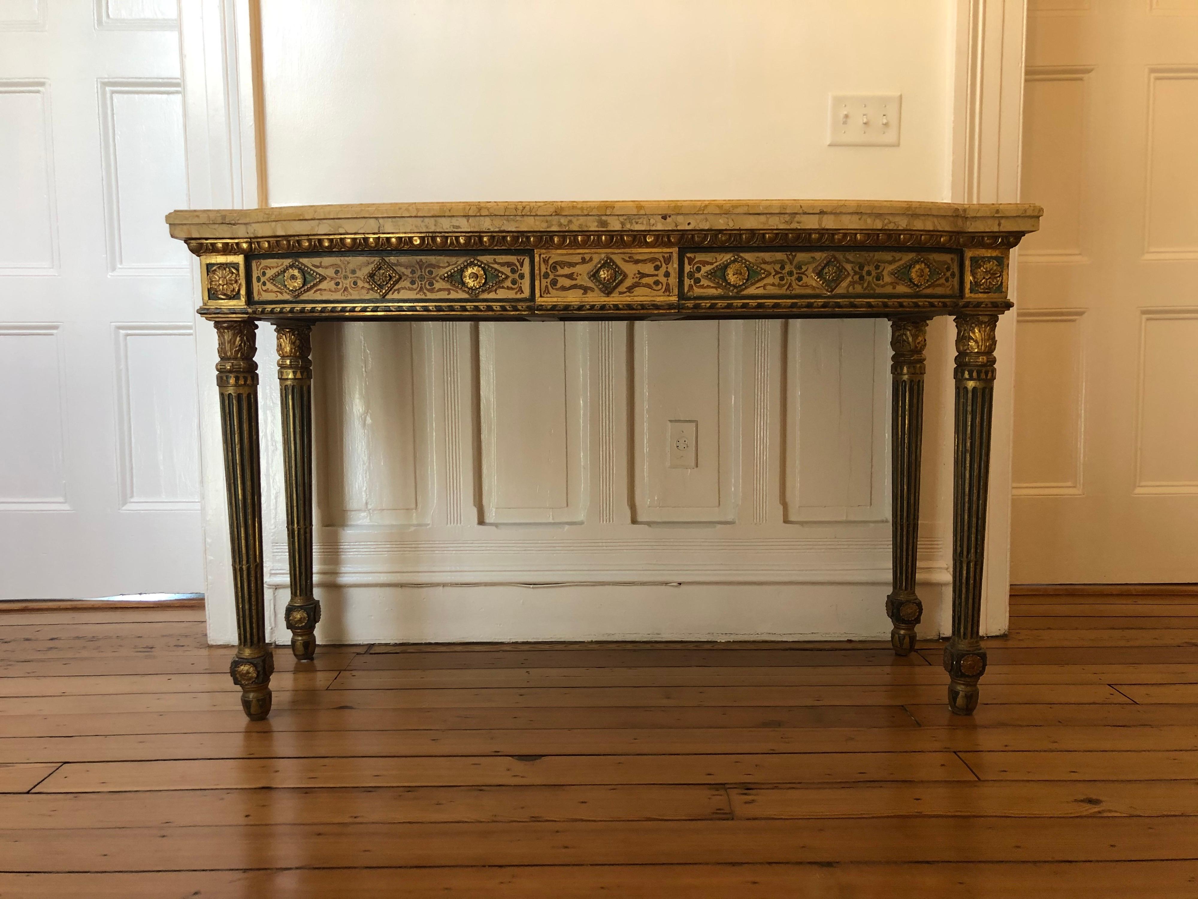 Elegant neoclassical Italian marble top console has a double marble above an Adam Style painted frieze with hidden drawers. The legs are decorated with craved gilt acanthus capitals above fluted legs that are gilt and painted. This console has a