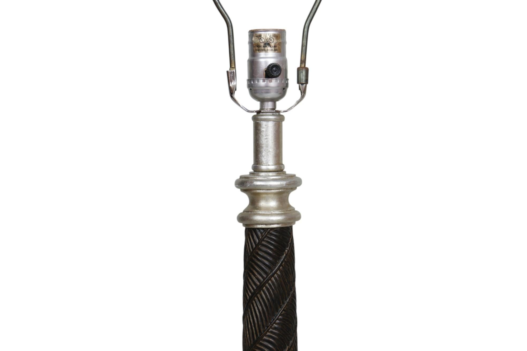 A neoclassical style table lamp. The slender central column is cast to give the look of being wrapped in palm leaves. The same palm leaf motif can be seen on the square base and on four rounded feet. Measures 5