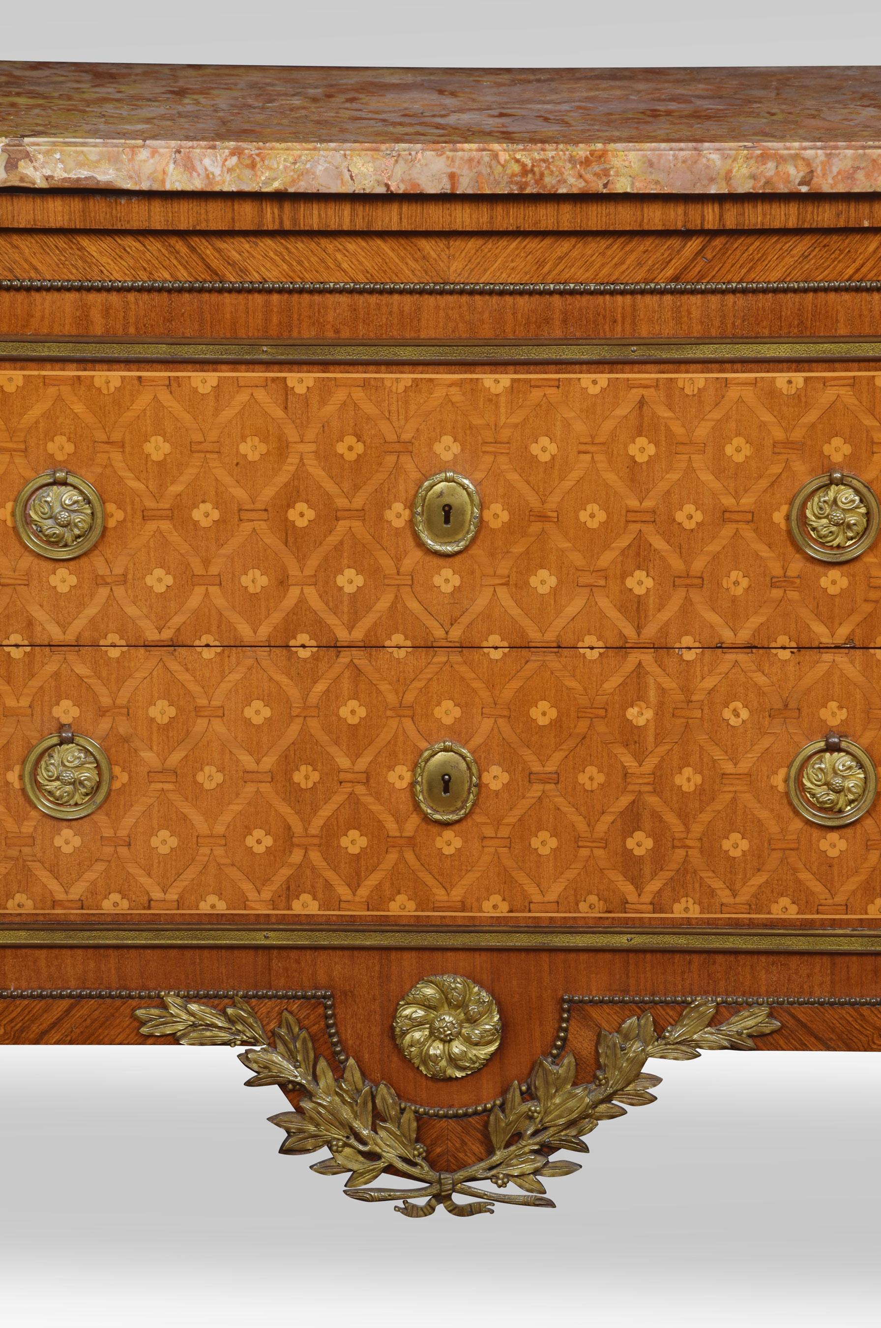 Neoclassical parquetry and gilt metal mounted marble-topped commode, the large canted pink-veined marble top above two deep drawers, the fronts inlaid with a flower trellis to the shaped apron below with gilt metal roundel and swags. All raised up