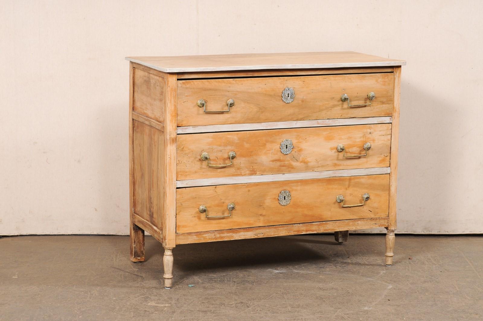 Una commode francese in legno sbiancato con una bella ferramenta dell'inizio del XIX secolo. Questa cassapanca antica proveniente dalla Francia presenta un piano di forma rettangolare sopra la cassa che ospita tre cassetti graduati di dimensioni