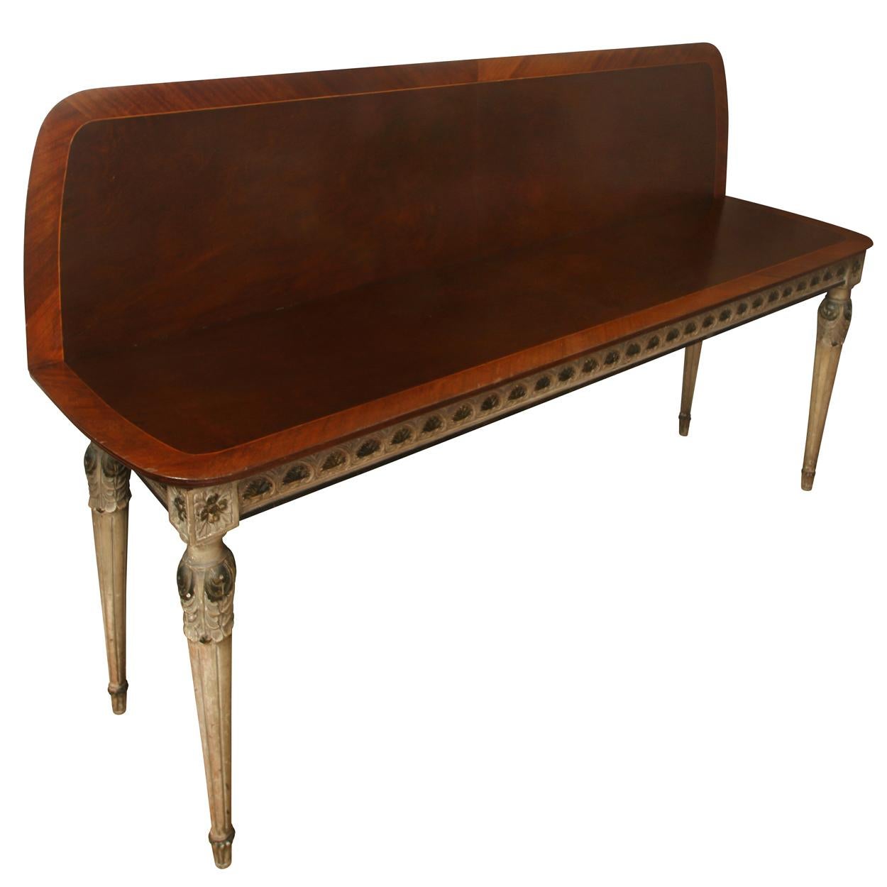 Une table console de style néoclassique métamorphosée avec des détails sculptés et peints. Le plateau en bois foncé est bordé d'une bande incrustée d'un bois de couleur plus claire et d'un motif complexe à chaque coin. Le tablier et les pieds peints