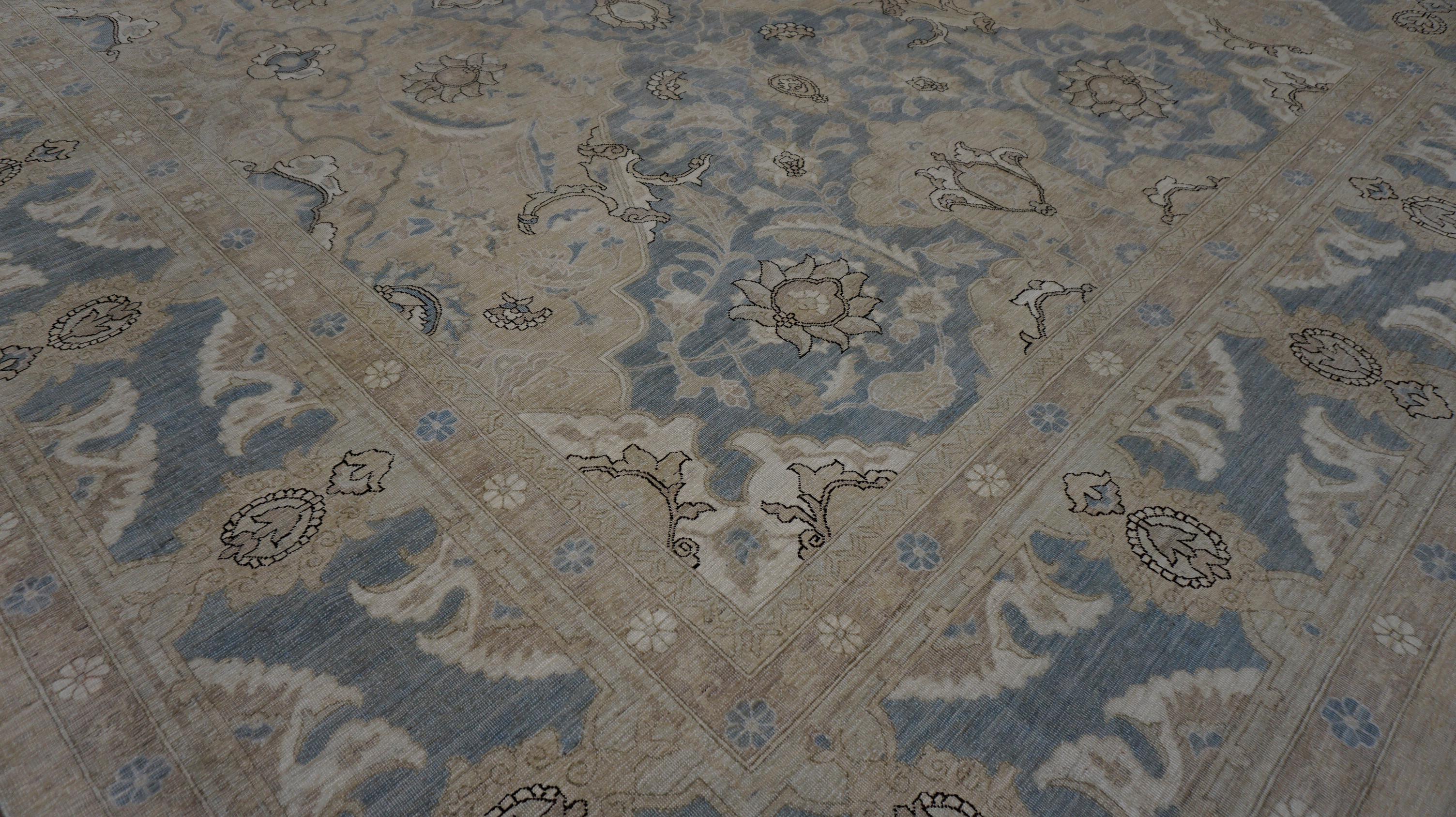 Esta alfombra de lana anudada a mano presenta un refinado motivo floral y botánico de inspiración vintage, tejido en una armoniosa mezcla de suaves tonos azul, tostado, marfil y topo. El intrincado campo central muestra una elegante disposición de