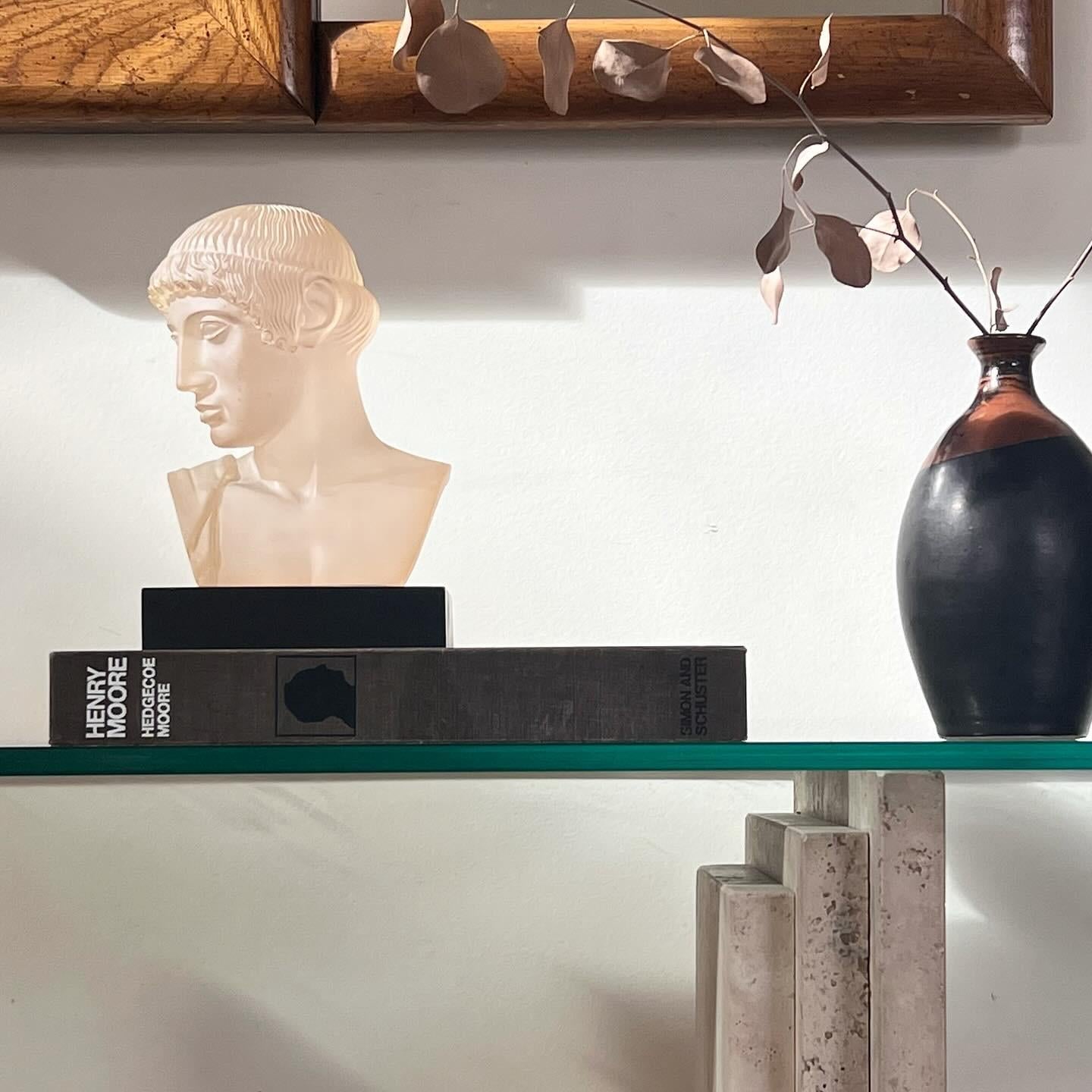 The neoclassical bust of a masculine Greek youth, late 20th century. Translucent resin - not dissimilar from alexandrite glass, which changes color depending on the light exposure - is here outfitted handsomely upon an ebonized wooden plinth. In