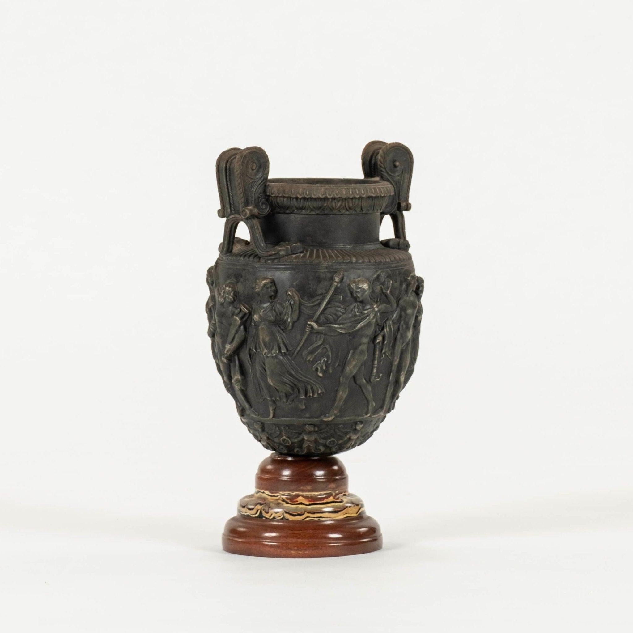 Vaso a urna della metà del XX secolo in stile Neoclassico con base in legno a fasce di marmo finto dipinto con una scena romana in bassorilievo. Solo per uso decorativo.