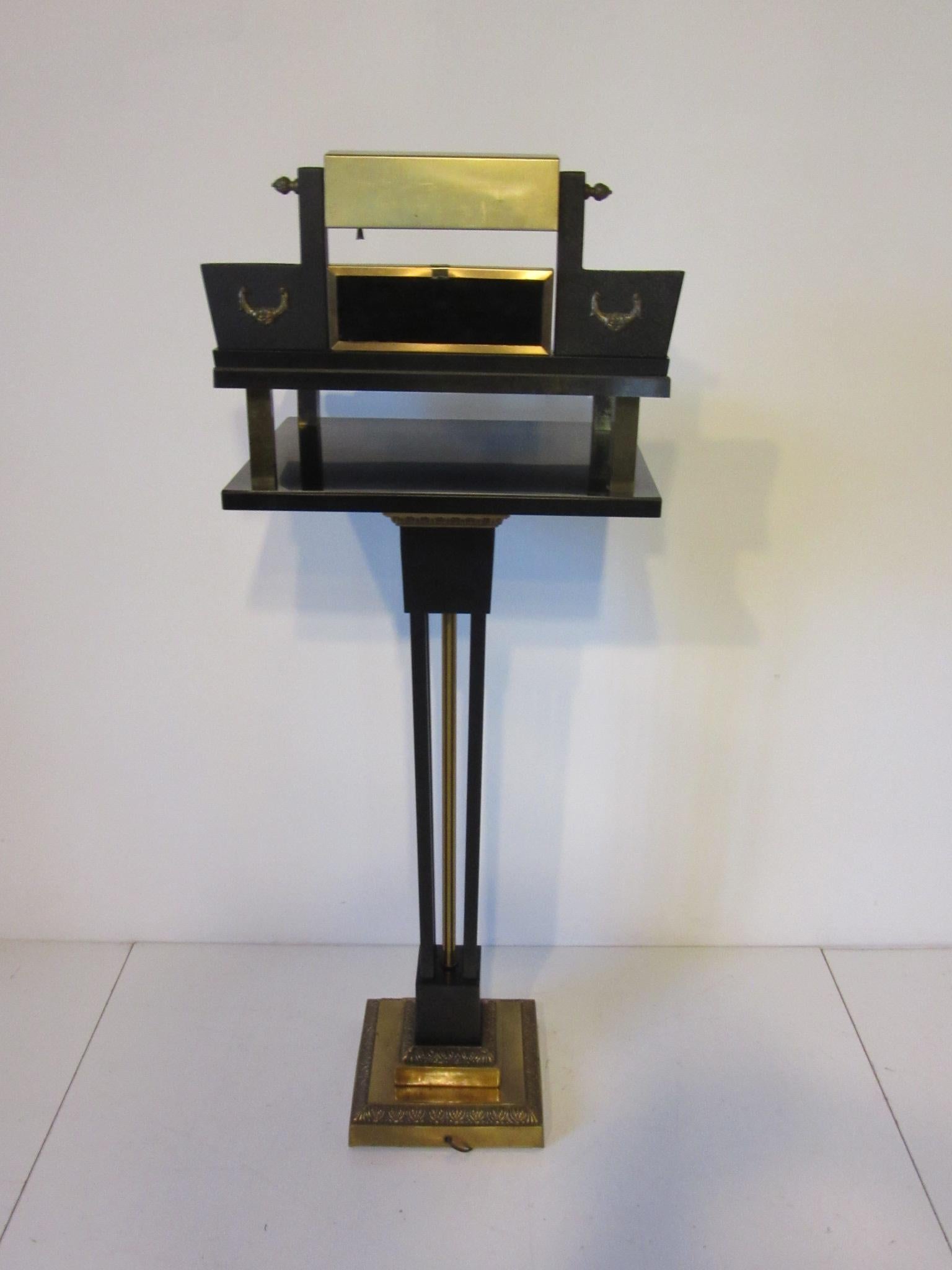 A Neoclassical lectern with black wood and metal construction , gilt metal and brass base and details with decorative designs. Card holders to each side of the writing surface with pen groove under centered lamp, perfect for that host or hostess