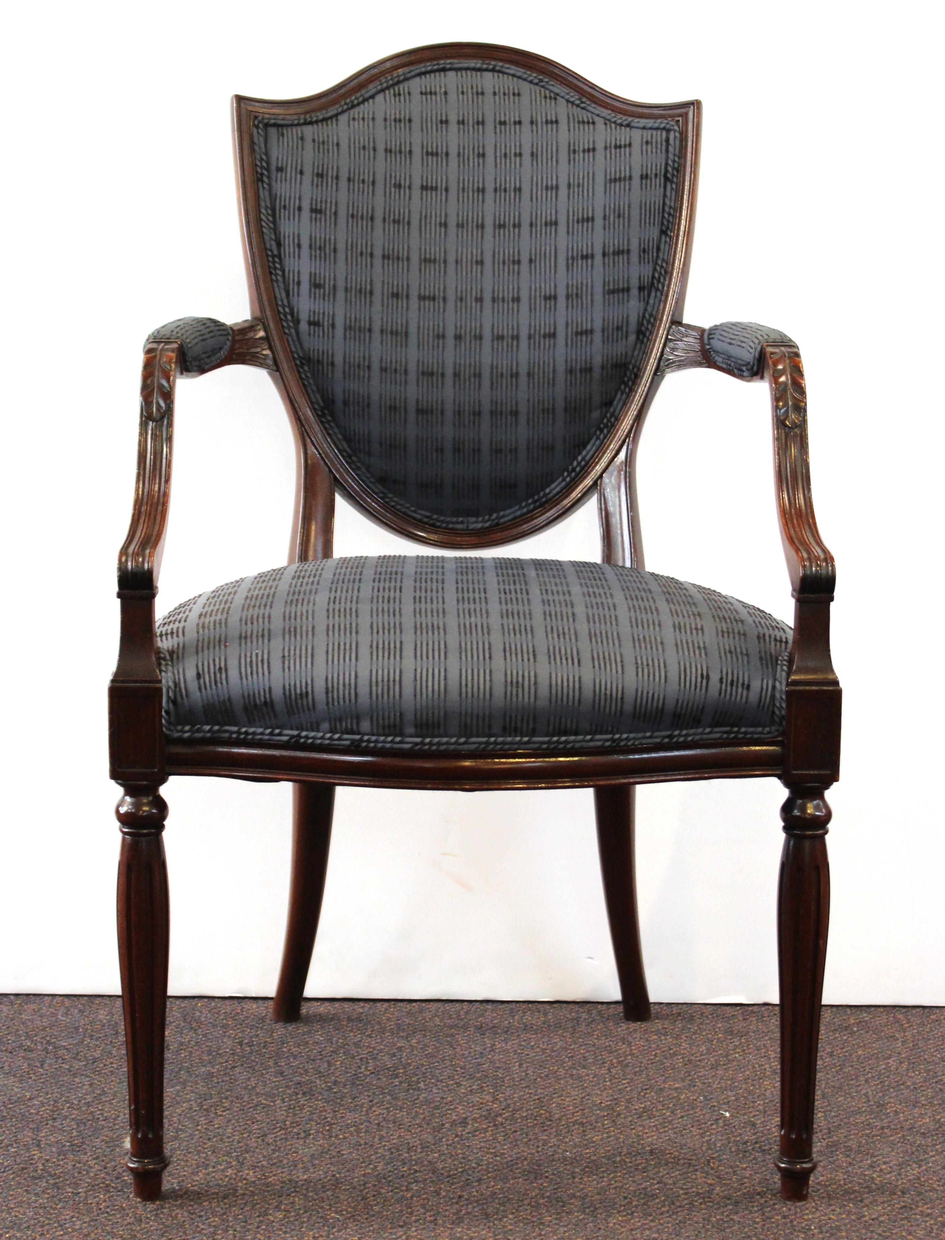 Pair of Neoclassical Revival style armchairs in carved wood with shield-shaped backs and neoclassical detailing on the armrests and modern upholstery. The pair is in great vintage condition with minor age-appropriate wear and use.