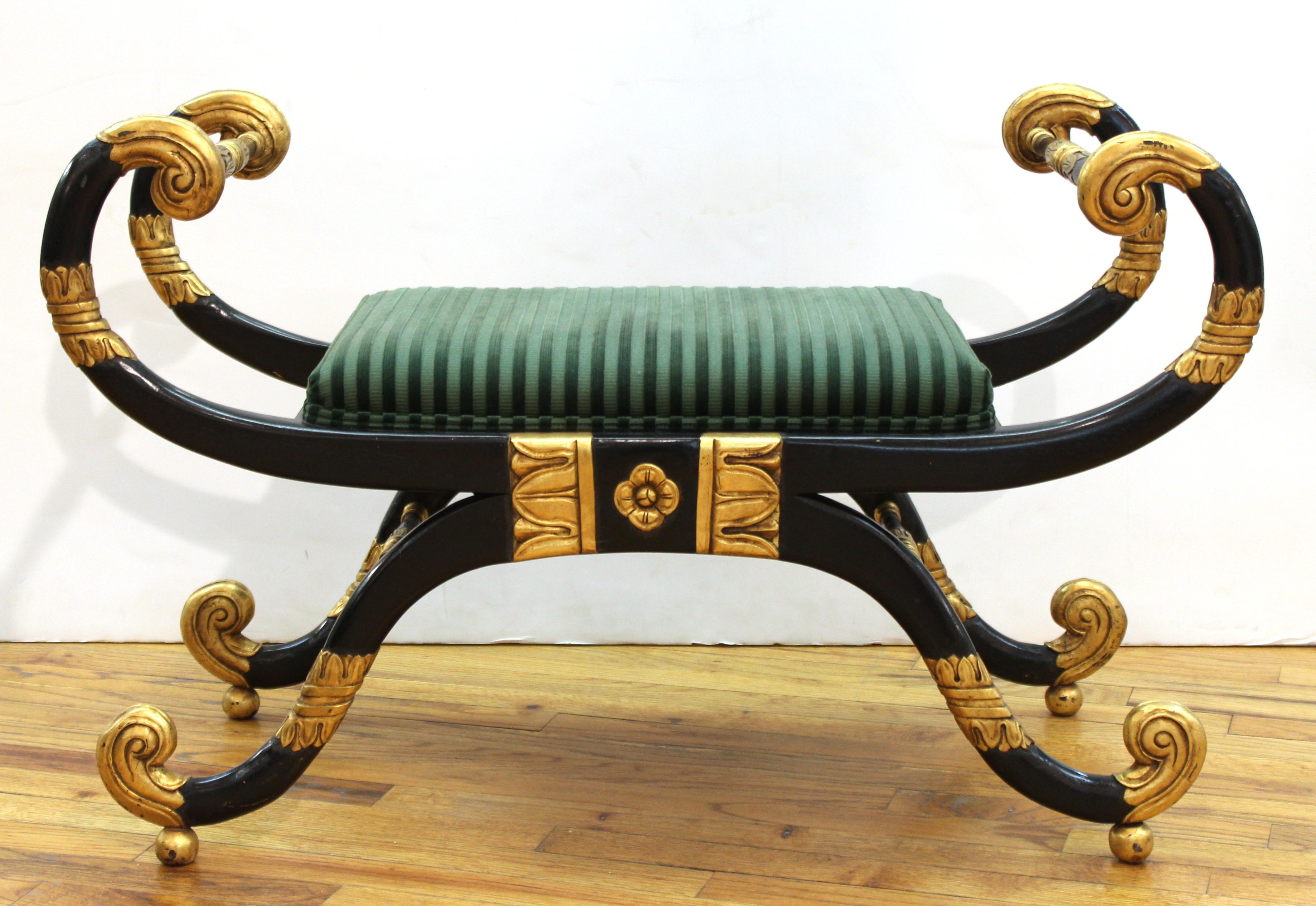 Neoclassical Revival style pair of Curule benches in ebonized and partially gilt carved wood. The pair has striped green upholstery. In great vintage condition with age-appropriate wear and use.