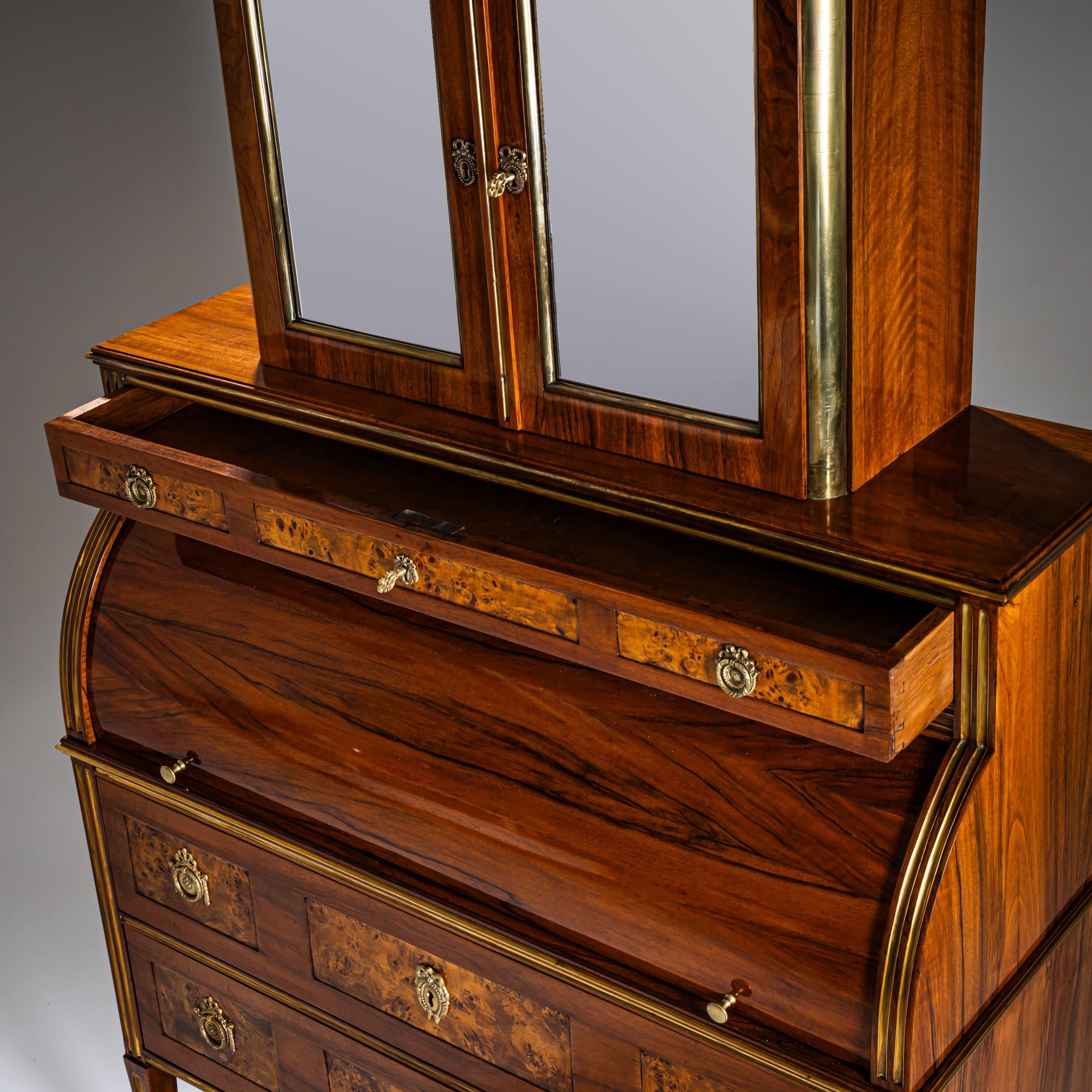 Refined neoclassical roll-top secrétaire standing on fluted square tapering legs with matching pilaster strips. The lower section features three drawers, topped by a mirrored two-door cabinet. The roll-top opens via a sliding mechanism to reveal six