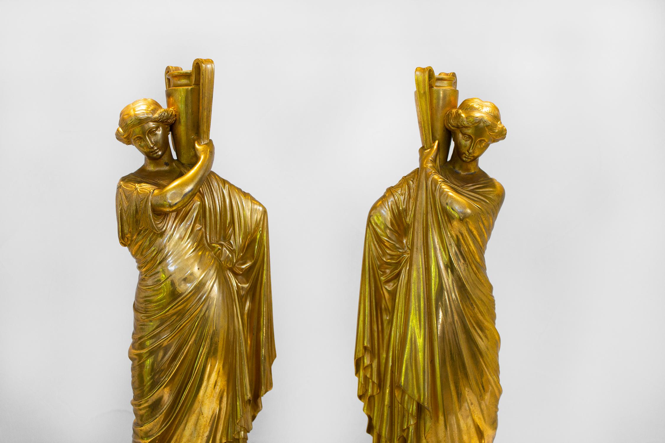 Gorgeous pair of antique golden cast bronze roman women on newly fabricated marble bases. They are hollow and the water jugs are open so they can be used to display an arrangement without water.