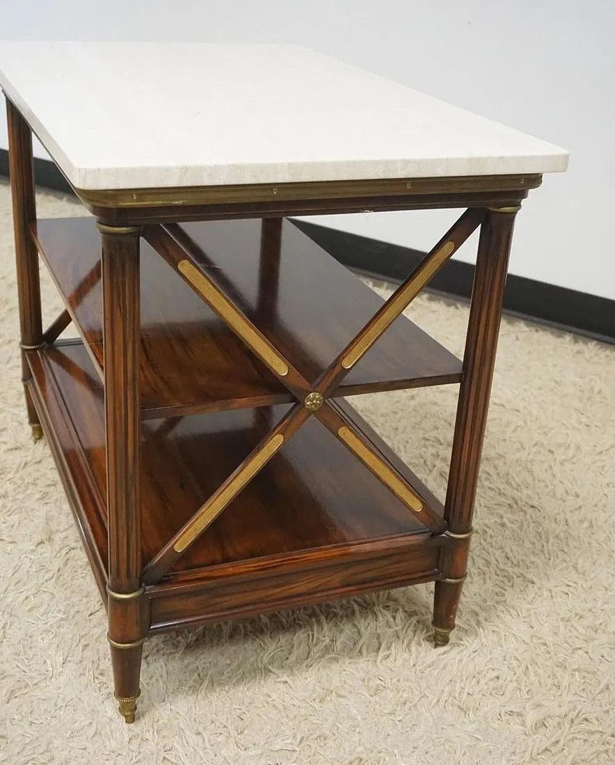 Elegante mesa auxiliar o de escritorio neoclásica de palisandro con patas estriadas que soportan un tablero rectangular de mármol blanco, 2 estantes y cajón , con una decoración de  monturas y ruedas de bronce dorado.

Dimensiones :   aprox. 26