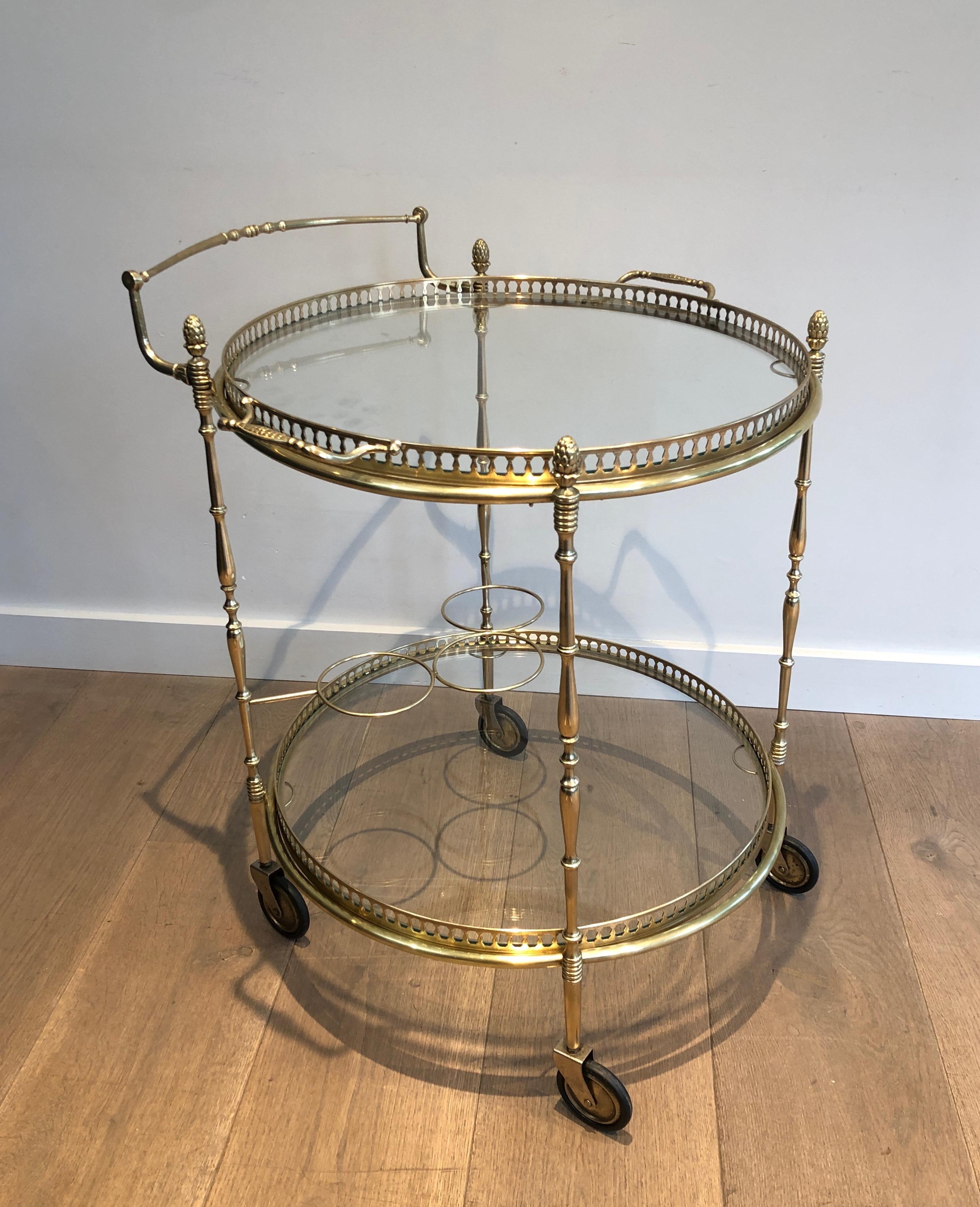 This neoclassical style round bar cart is made of brass. This drinks trolley has two removable trays. This is a work by famous French designer Maison Bagués. Circa 1940.