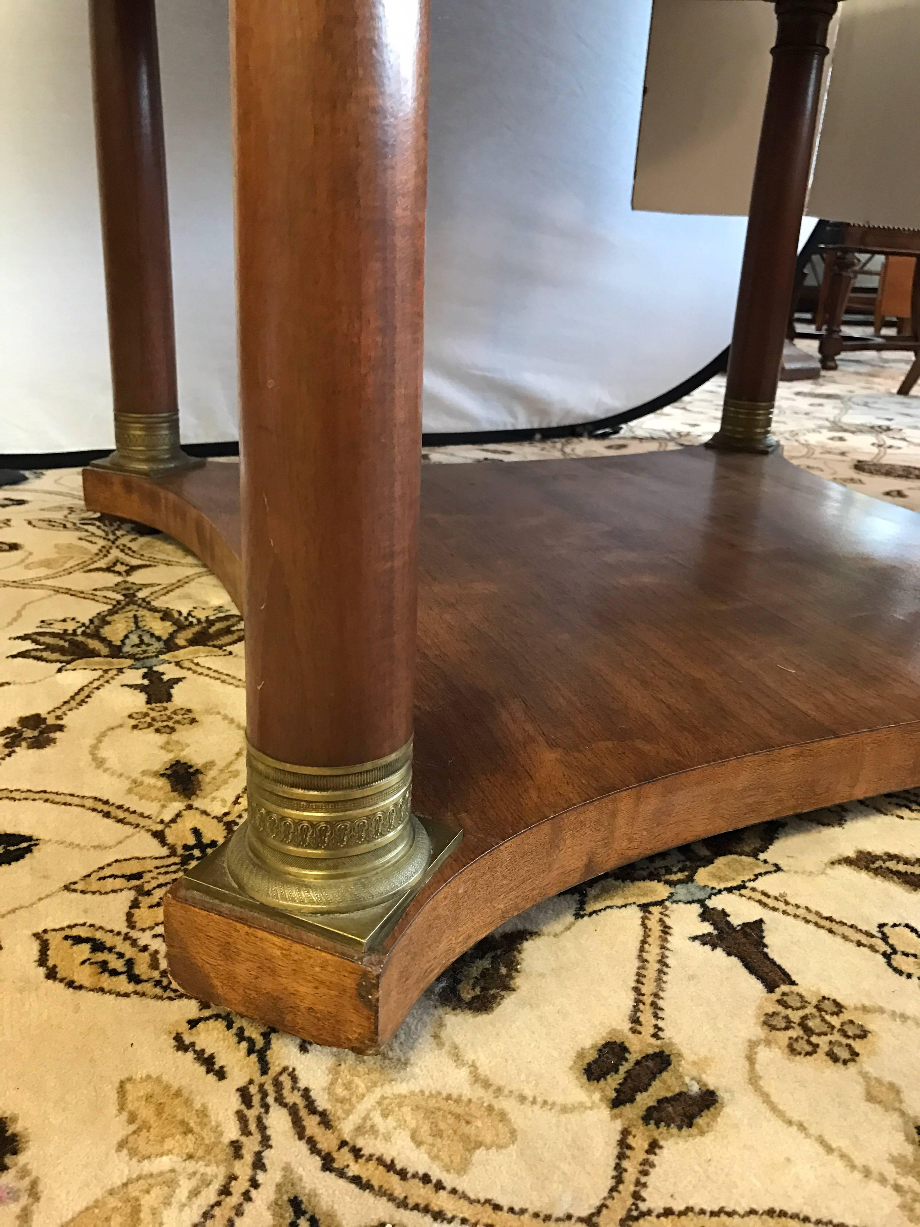 Large round dining table rests on four column legs with brass detail. Includes three leaves. Manufactured by famed US maker Potthast Brothers.
 