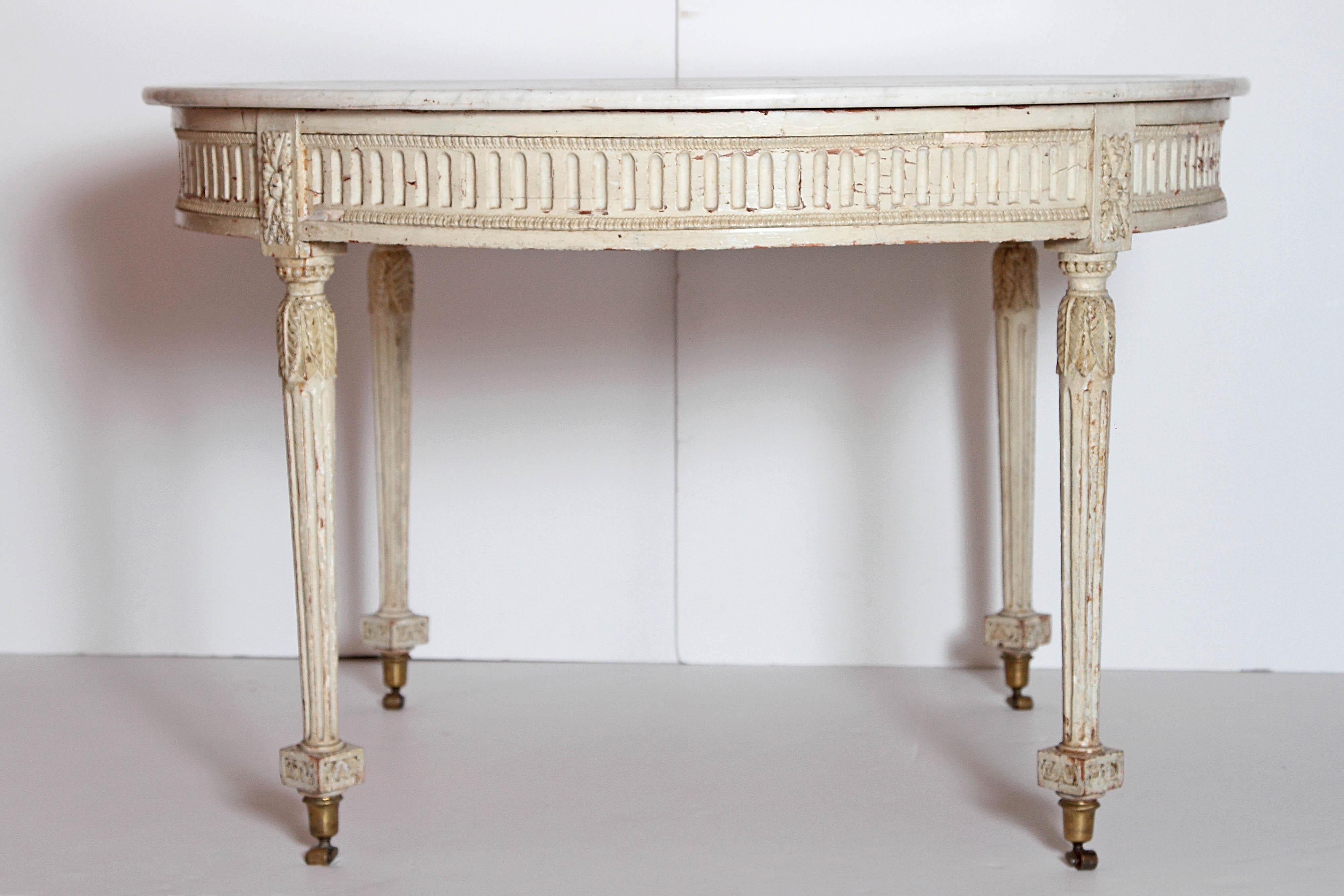 A painted neoclassical round table with its original white and grey veined marble top having an incised reeded design. The table base is painted in a soft white palette that compliments the marble top and the neoclassical lines. The marble top sits