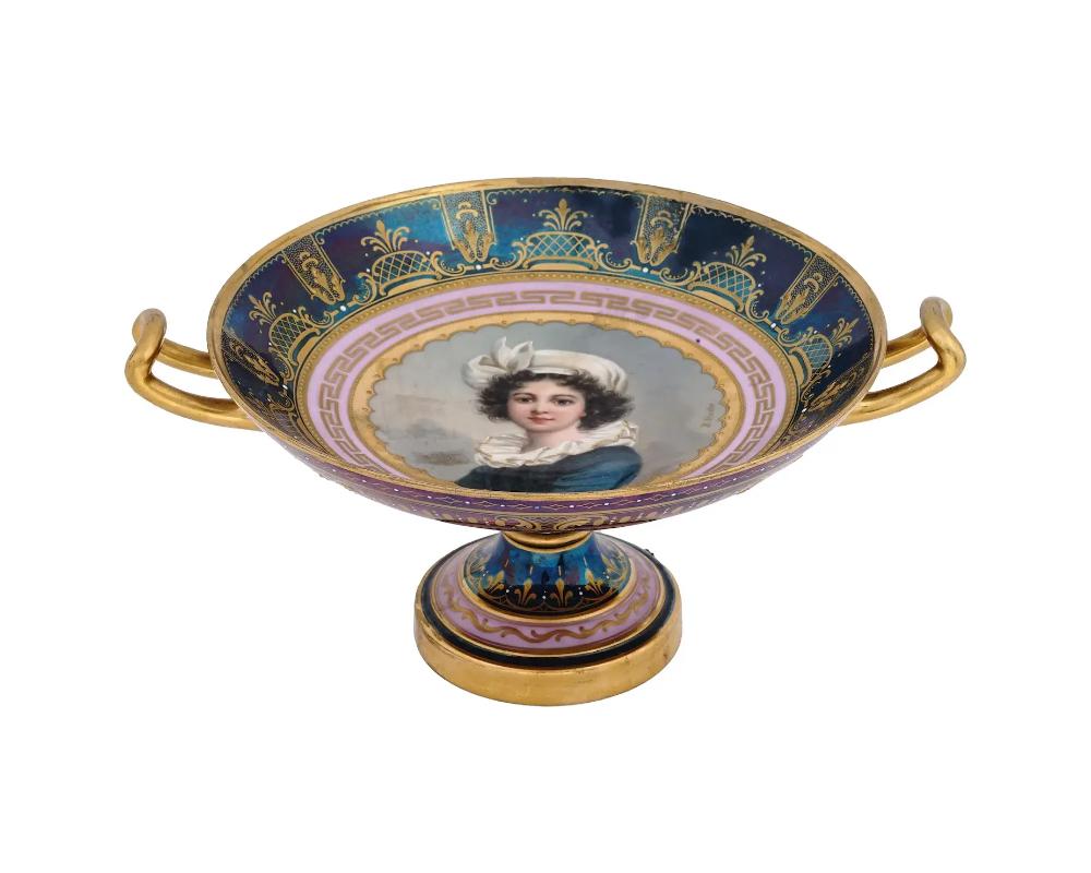 An antique late 19th-century Neoclassical porcelain tazza or footed serving plate of kylix shape by Royal Vienna, an Austrian porcelain manufacturer. Iridiscent blue and purple rims and foot with gilt ornaments. The central part of the plate is