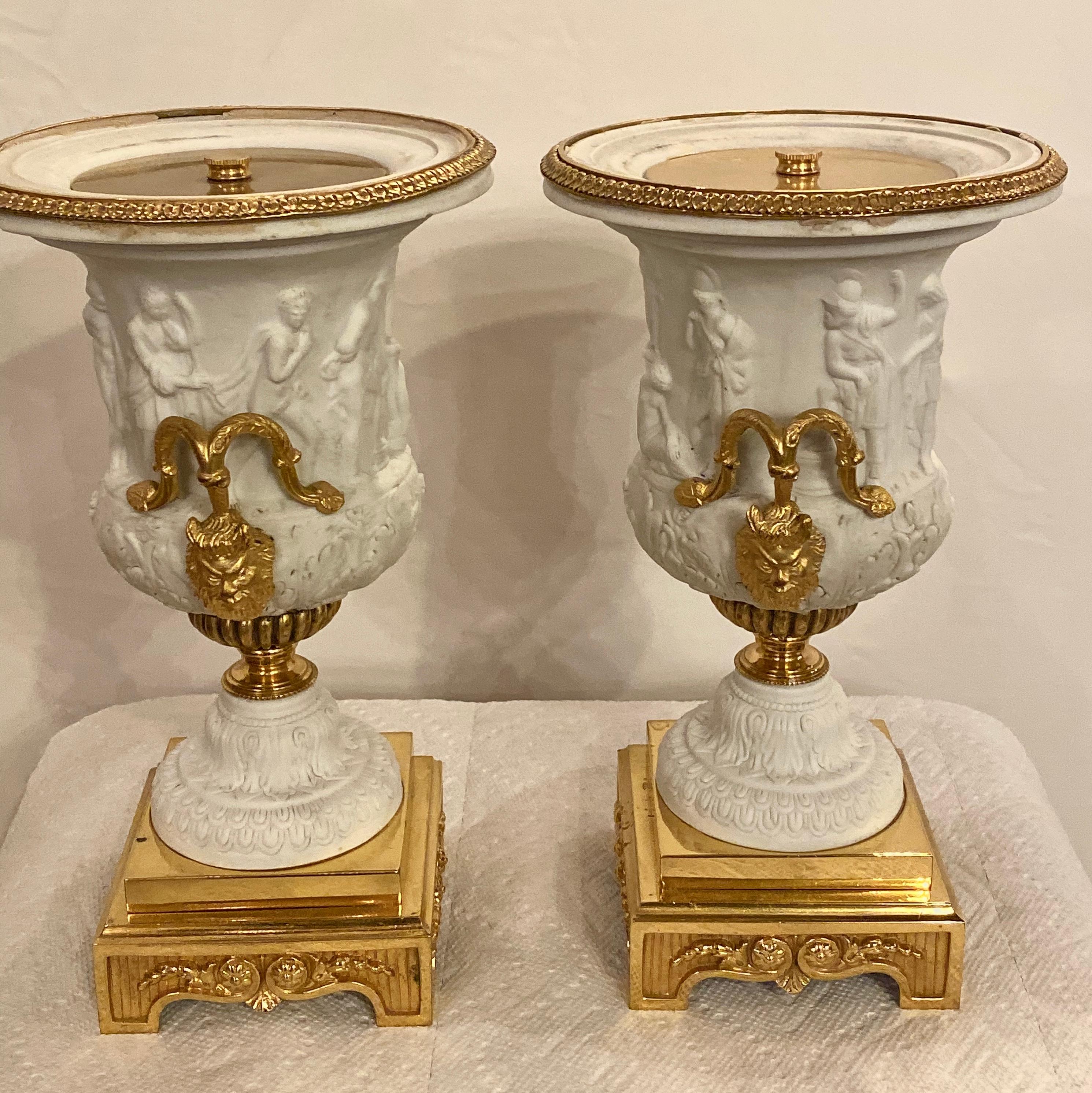 Neoclassical pair of Sevres Parian and doré bronze mounted Urns or Vases circa 1920s. This spectacular pair of table vases having doré bronze bases supporting a finely cast stamped Sevres Grecian style vase depicting various woman and men working or