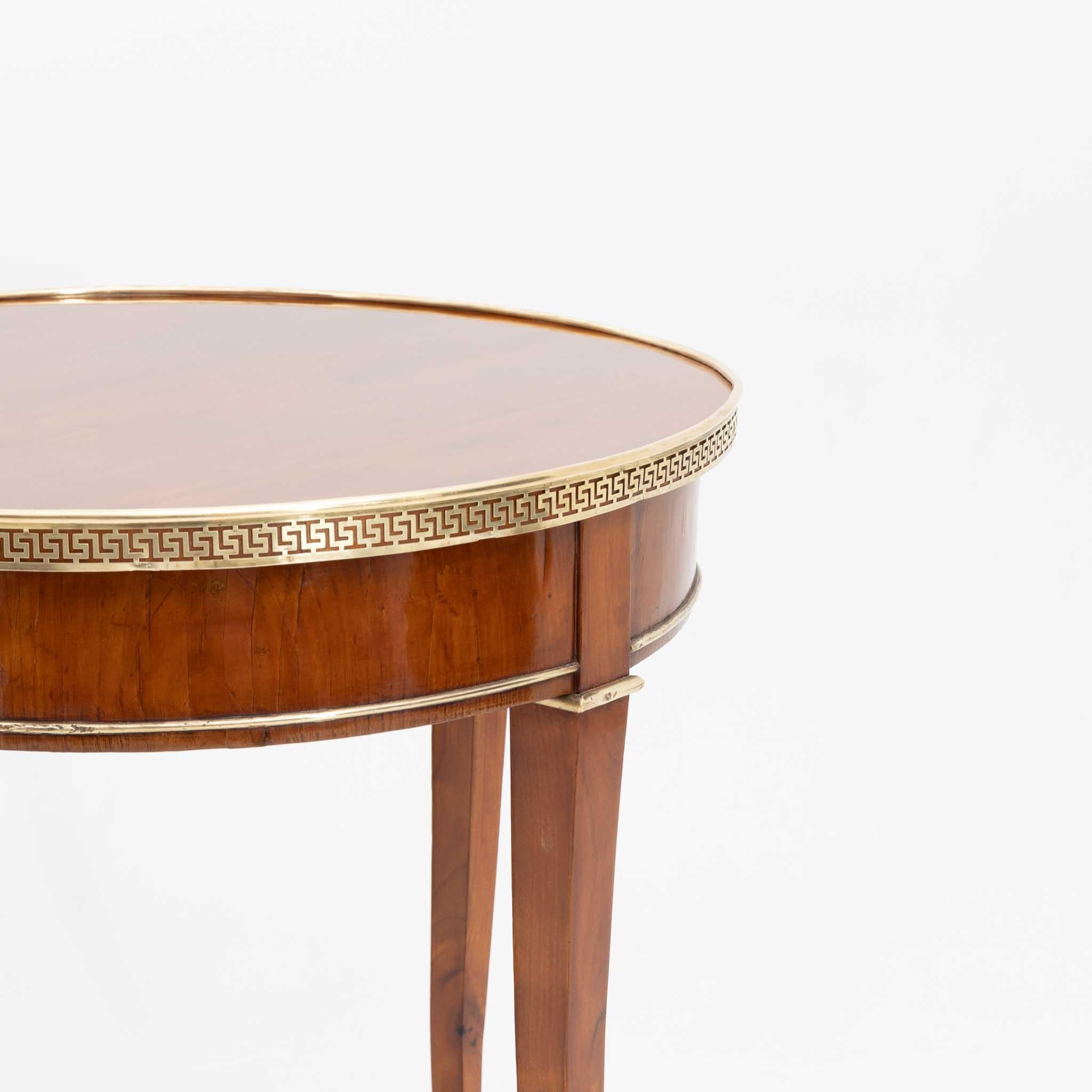 Neoclassical side table in cherry with surrounding brass strip in the form of a meander band and slightly curved square-pointed feet.