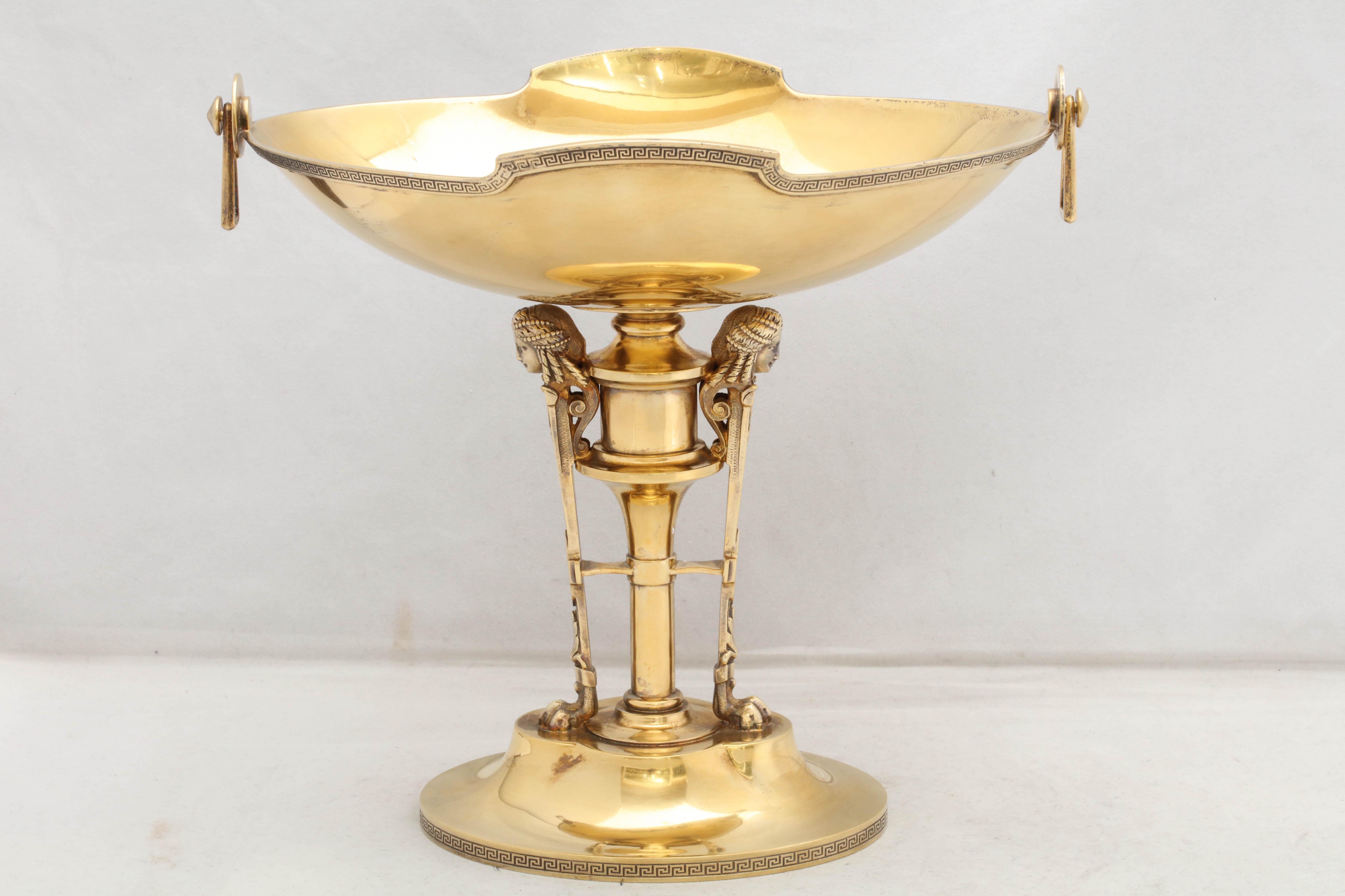 Neoclassical, sterling silver gilt centrepiece, Gorham Manufacturing Co., Providence, Rhode Island, circa 1865. Dish is oval in form and has pendant handles that move. Stem is flanked by pilasters topped by busts. Greek key borders on dish and base.