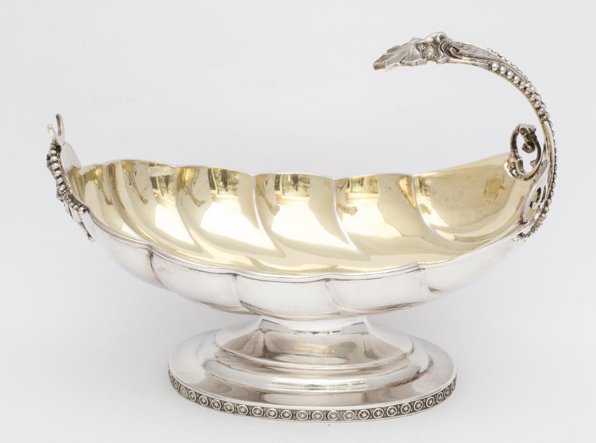 Neoclassical, sterling silver, parcel gilt, pedestal based sauce/gravy boat, New York, Ca. 1870, Wood and Hughes - makers. Shell - form scalloped interior is gilded; bead work motif on handle is continued on base. U-shaped opening on top of