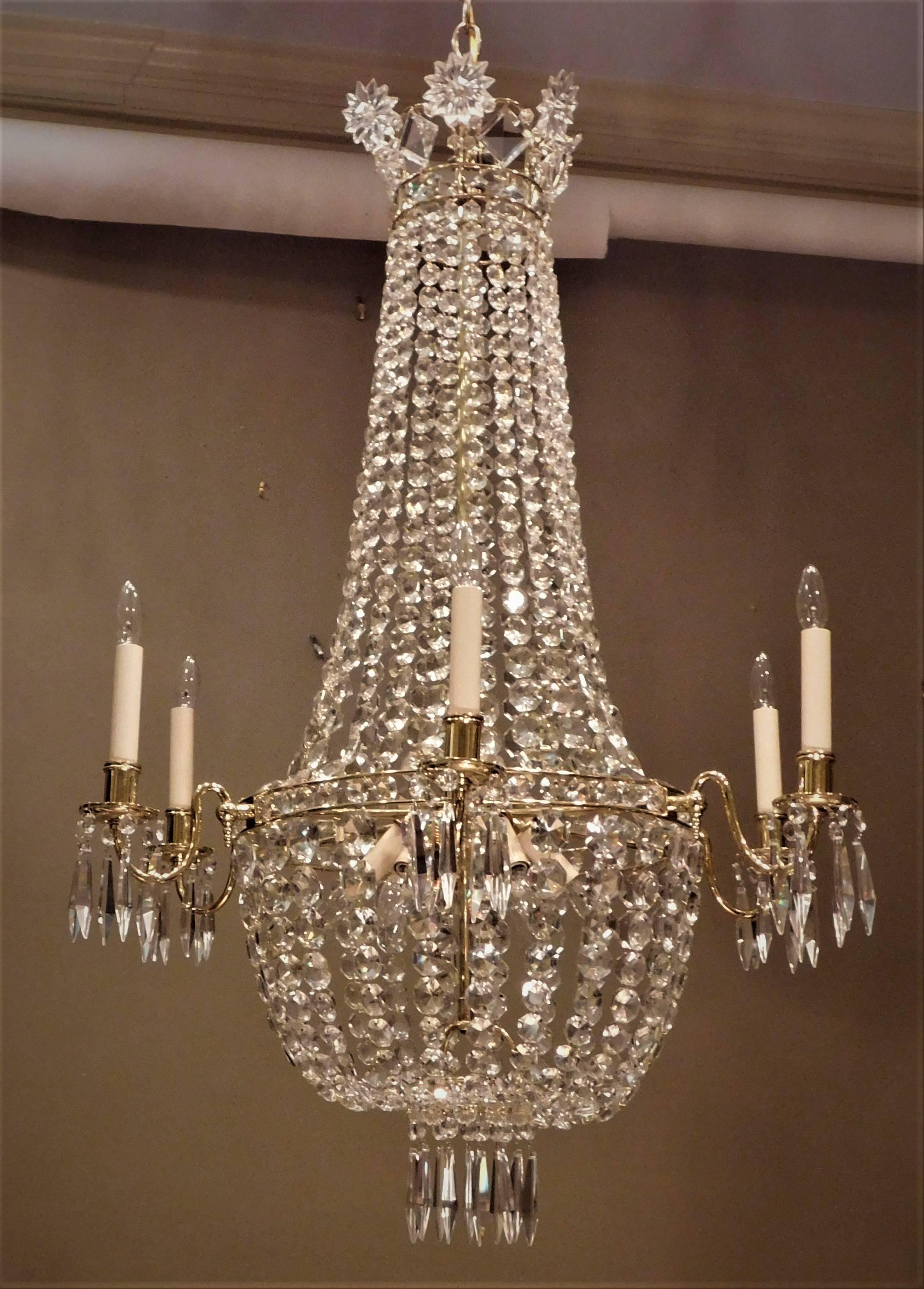 Solid brass frame with English cut crystal. Six lights arms on outside ring and a cluster of six lights inside, giving a large amount of light and dramatic glow. Crystal star crown is quite distinctive. Ceiling cap, hanging hardware, and 1' of chain