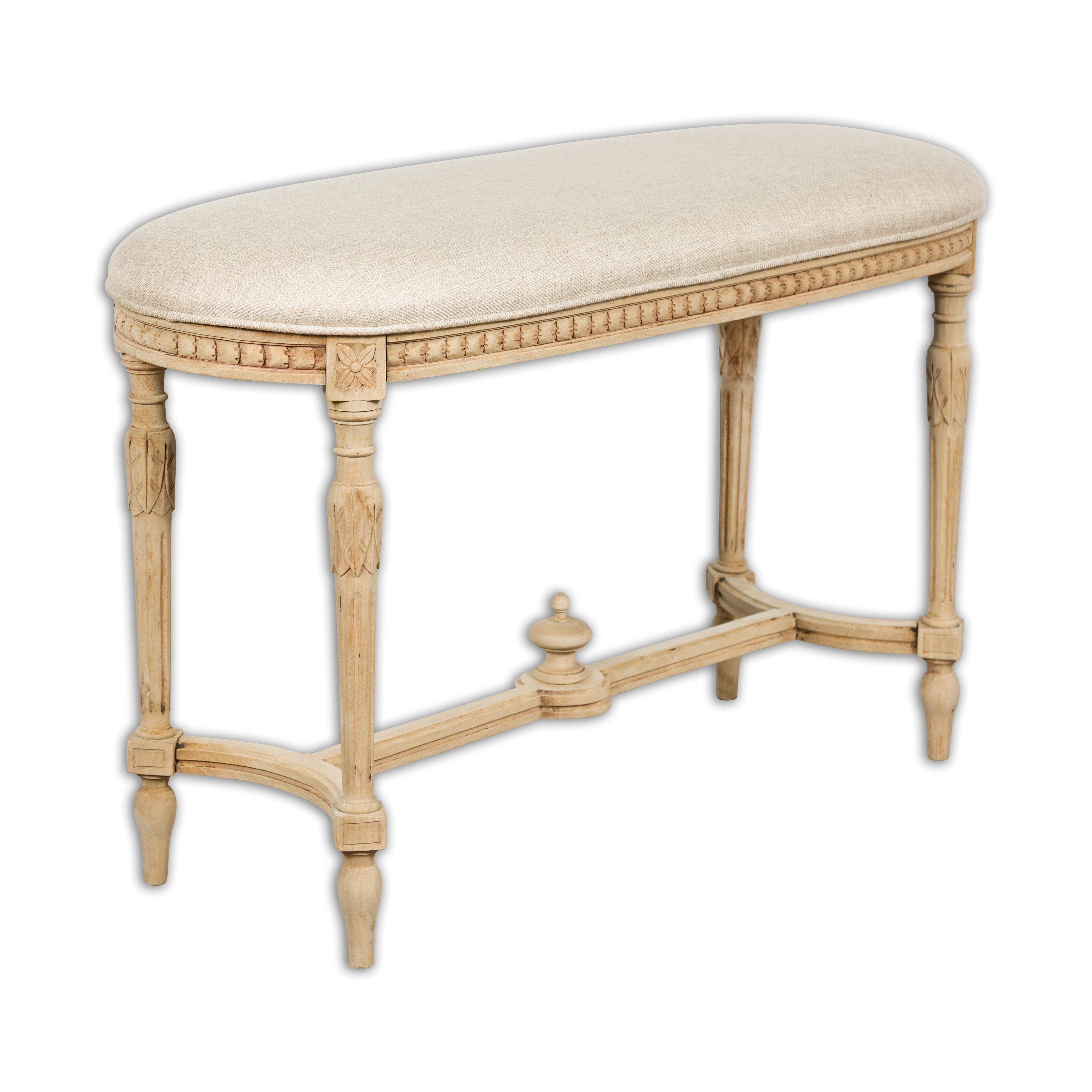 A French Neoclassical style walnut bench from circa 1900 with carved décor, fluted carved legs on arrow feet and cross stretcher. Imbued with the timeless elegance of the Neoclassical style, this French walnut bench from circa 1900 boasts a
