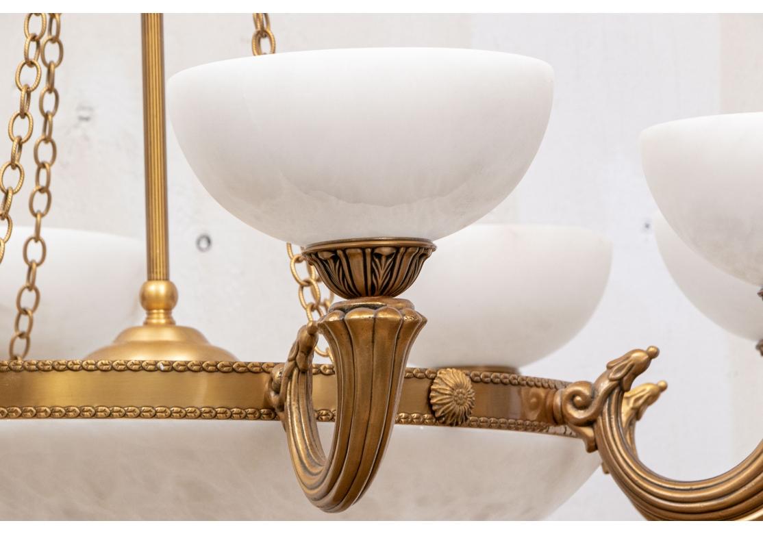 Finely crafted in brass, the eight lights with white alabaster cup form light shades on the horn form arms. A large white bowl connects the lights. The whole suspended on four chains connected to the leafy two-part top mount with loop. Along with a