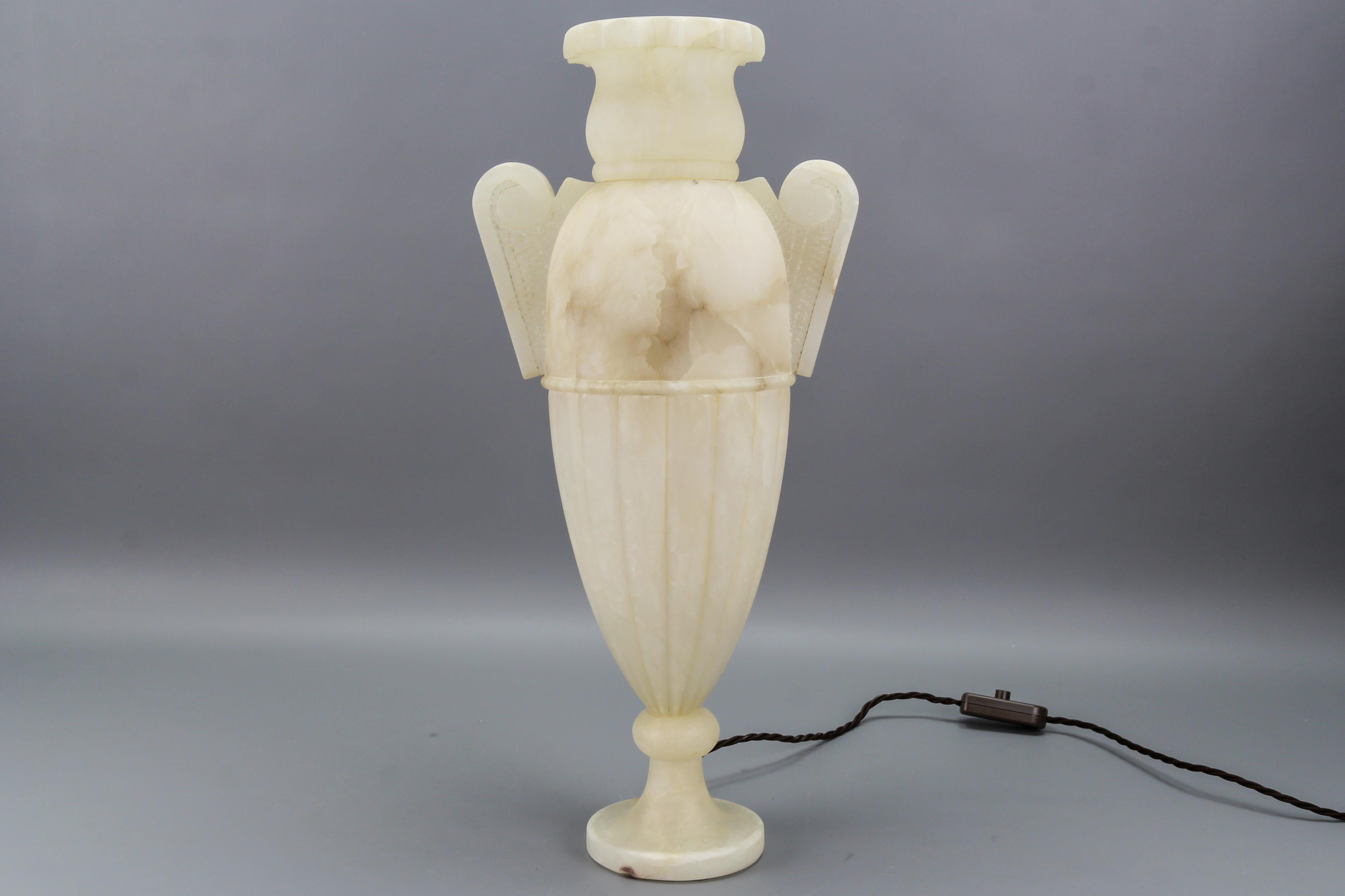 Neoclassical style amphora-shaped ivory and light brown veined alabaster lamp, Italy, circa the 1930s.
Impressive Italian Neoclassical style amphora-shaped lamp made of beautifully veined alabaster. The lamp lits from within and the light shining