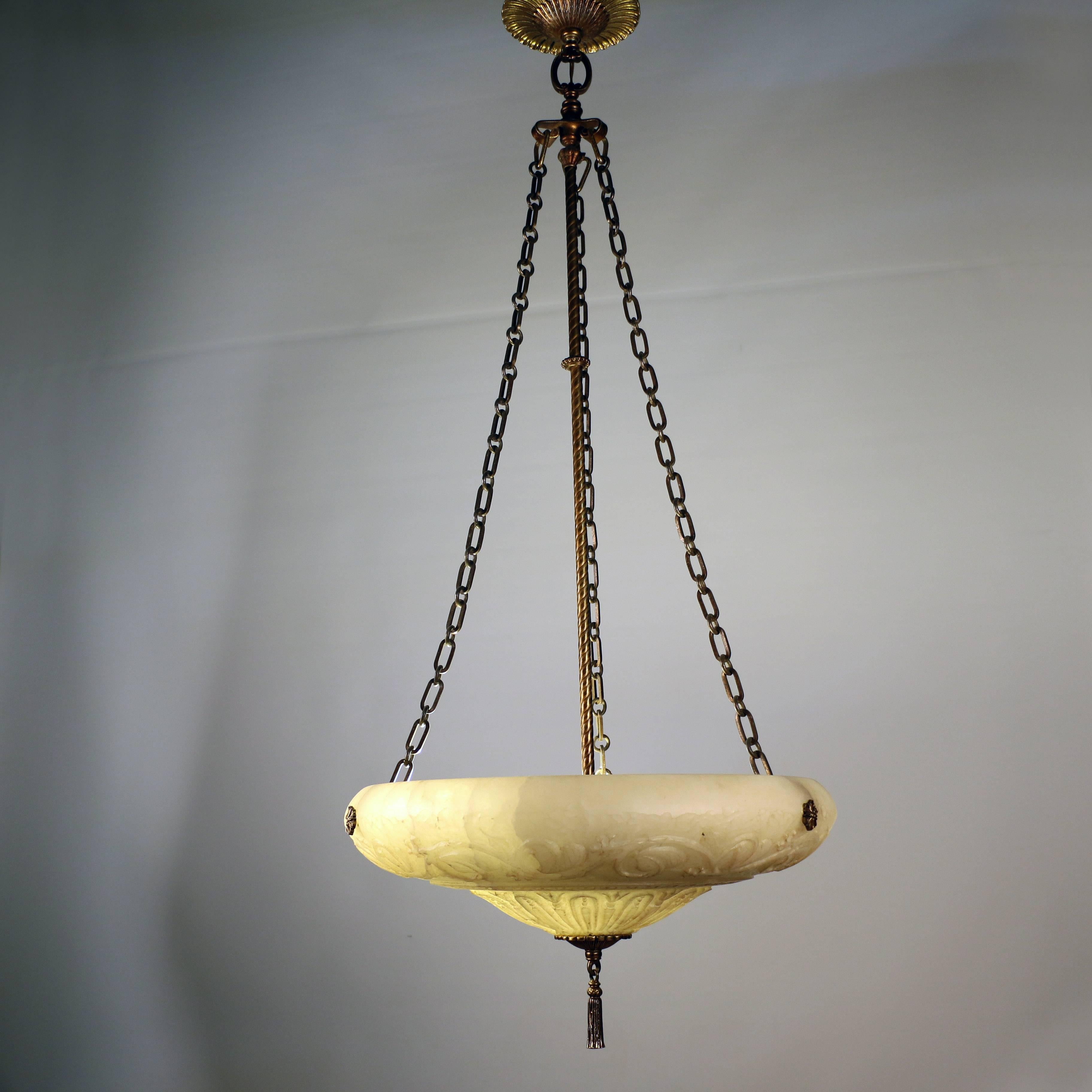 Carved alabaster three-light ceiling fixture with foliate gilt bronze canopy with three bronze chains supporting the sculpted alabaster bowl, ending in tasseled finial.