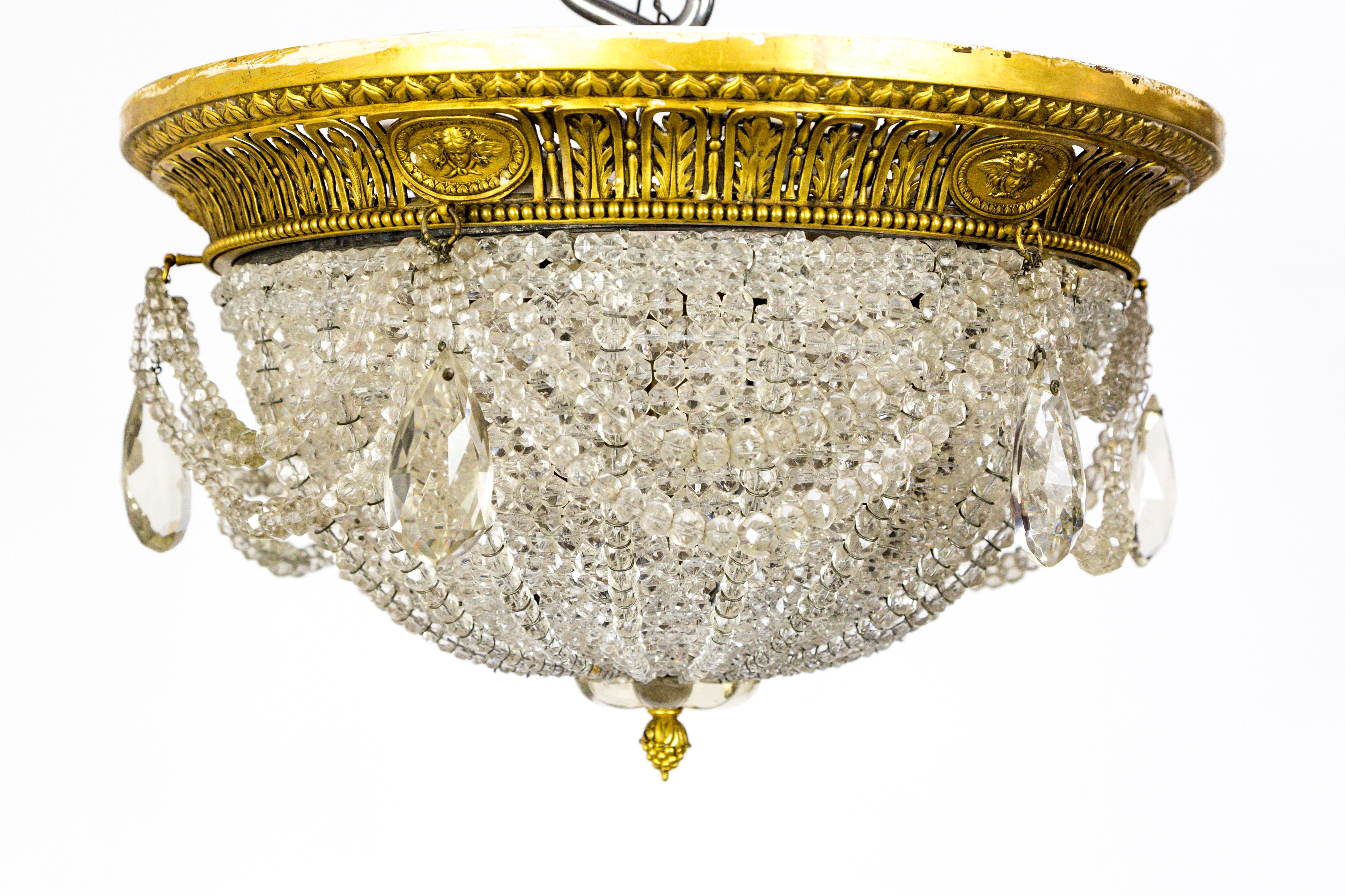 A pair of luxurious, rope crystal ceiling mount domes in neoclassic style. Finished with gilded metal mountings, reed bead, acanthus leaf details, and acorn finial. American, circa 1910. Three medium, ceramic sockets and weighty metal base.