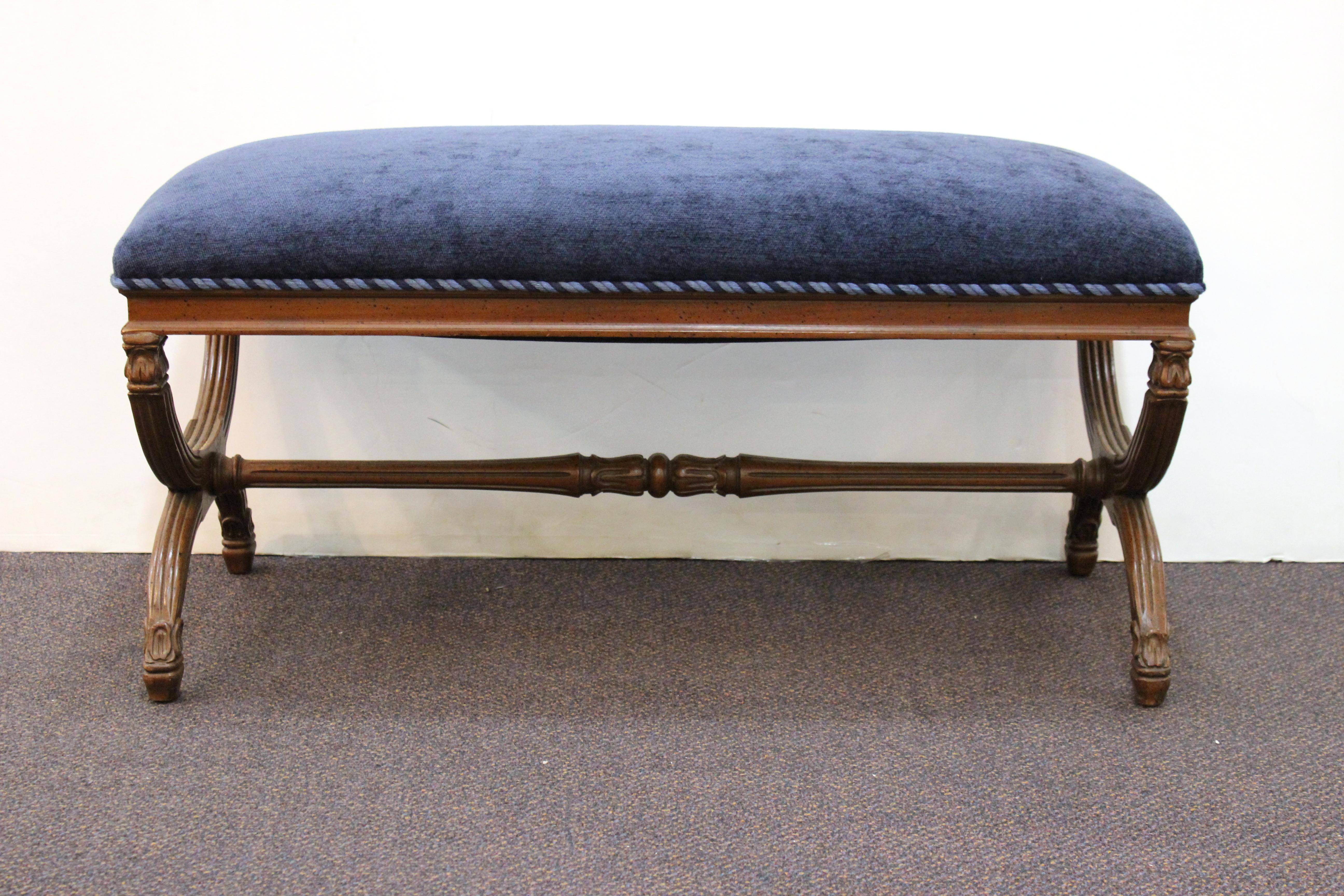 Neoclassical style bench produced in the United States during the 1970s. The bench is recently reupholstered in navy chenille with braided trim. The curved carved base is crafted from walnut. Despite some wear appropriate to age and use the bench