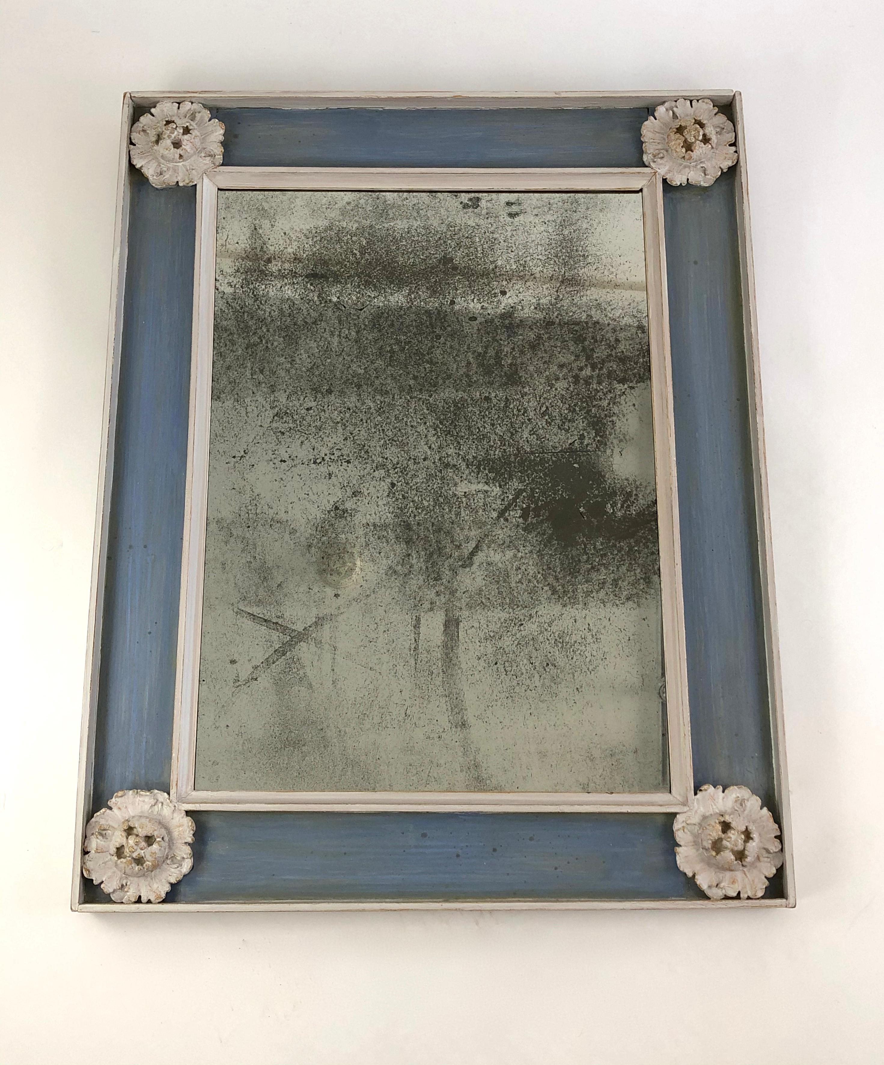 A rectangular neoclassical style slate blue and white painted frame, with deeply carved applied rosettes in the four corners and fitted with an antiqued mirror glass plate.