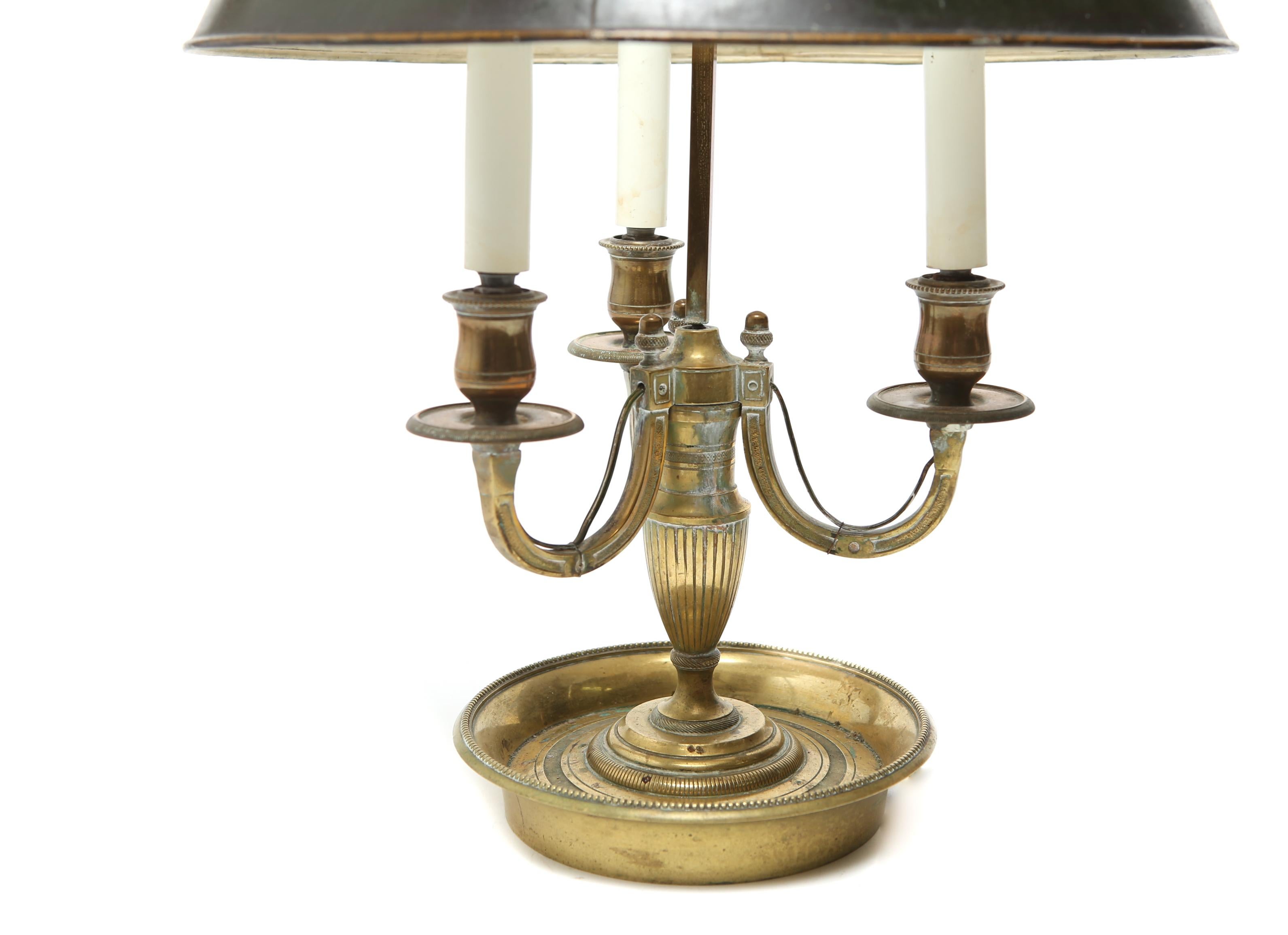 Neoclassical style bouillotte lamp with a three-light gilt bronze reeded urn-form base and with U-form candelabra supports. The piece has a laurel wreath finial and comes with a black toleware shade. In great vintage condition with age-appropriate
