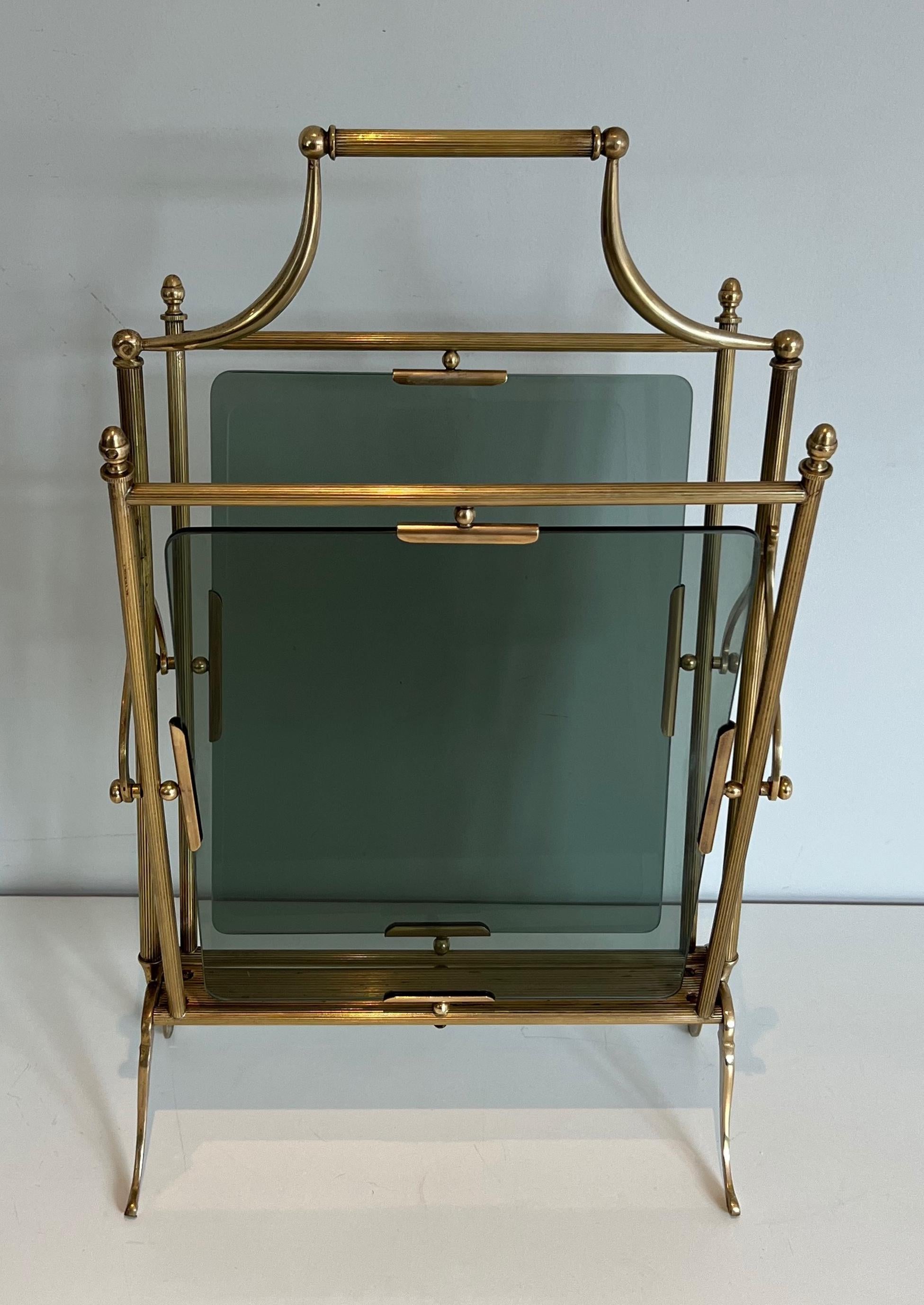 Questo simpatico ed elegante portariviste in stile neoclassico è realizzato in ottone con vetro bluastro sui lati. Questa è un'opera francese di Maison Jansen. Circa 1940.