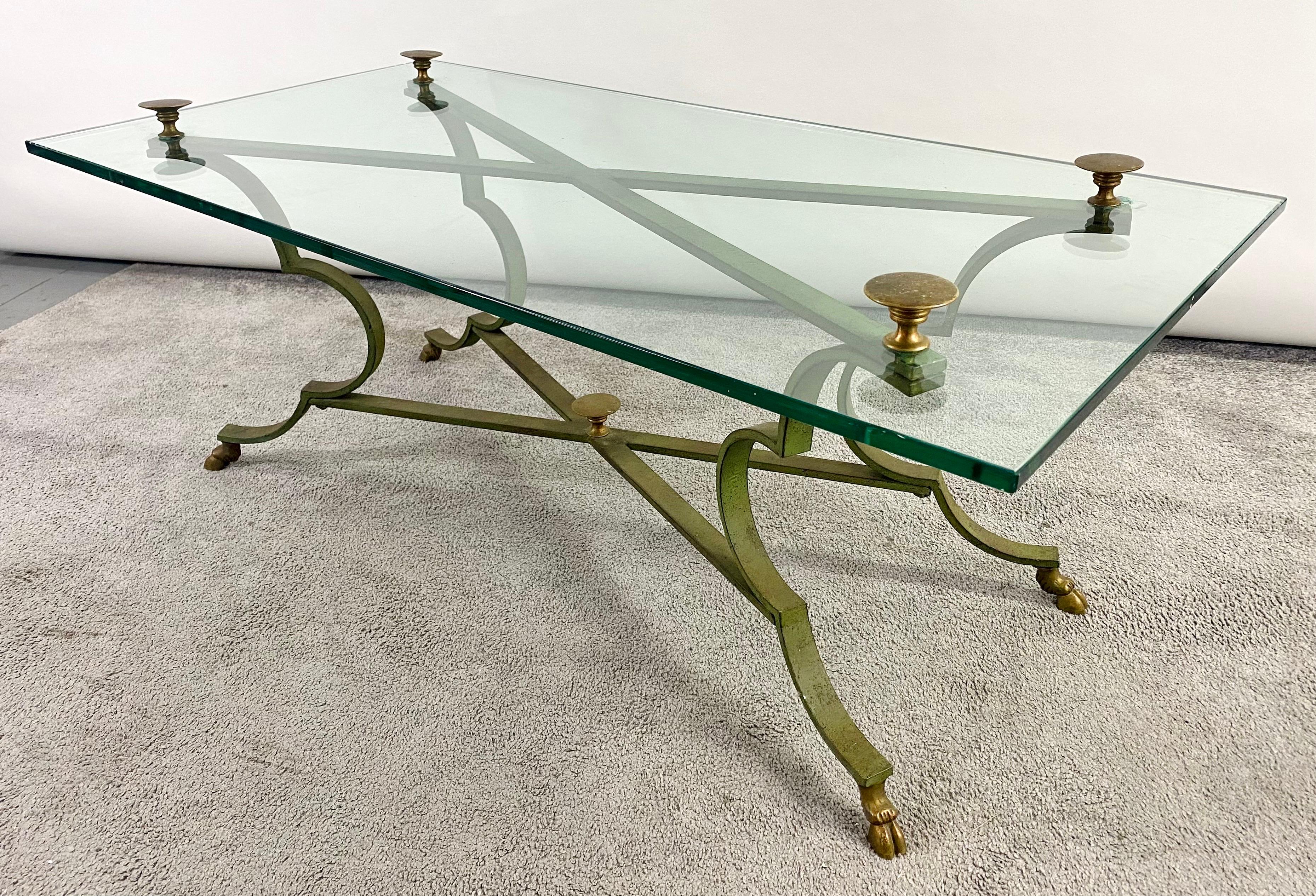 A stunning Neoclassical style brass and cast iron coffee table. The table thick glass top having protruding brass decorations on top and resting on a finely 
antiqued X shaped iron base . The base is beautful carved showing elegant curves and