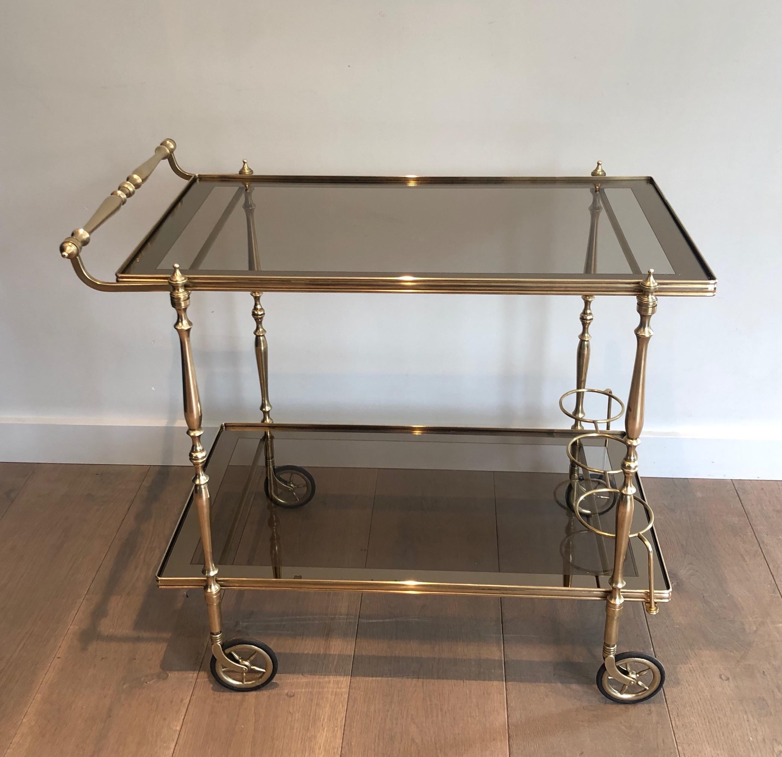 This neoclassical style bar cart is all made of brass with smoked glass, surrounded by a darker line. This drinks trolley is a French work, in the style of famous Maison Jansen, circa 1970.
